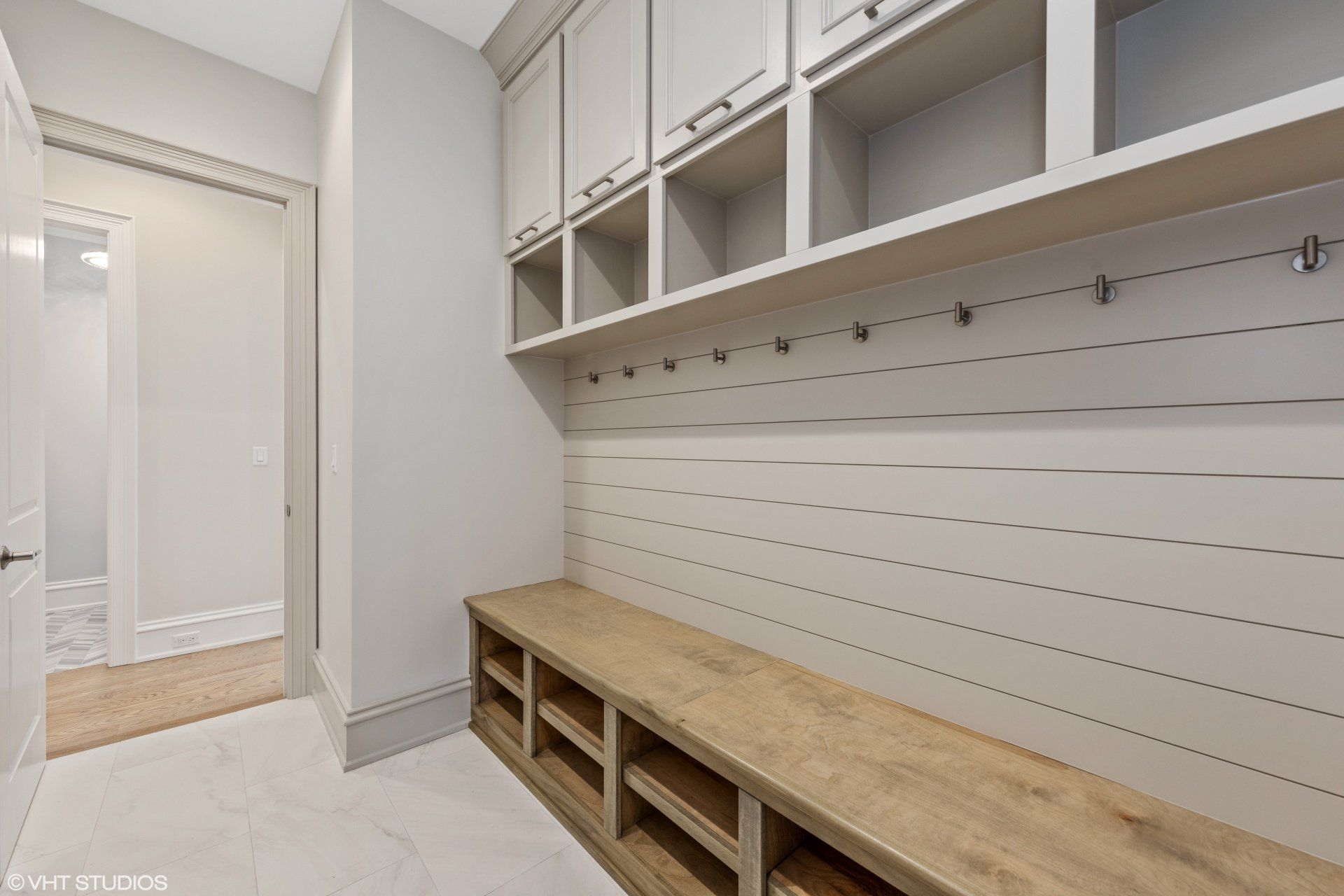 A mud room with a wooden bench and lots of shelves.