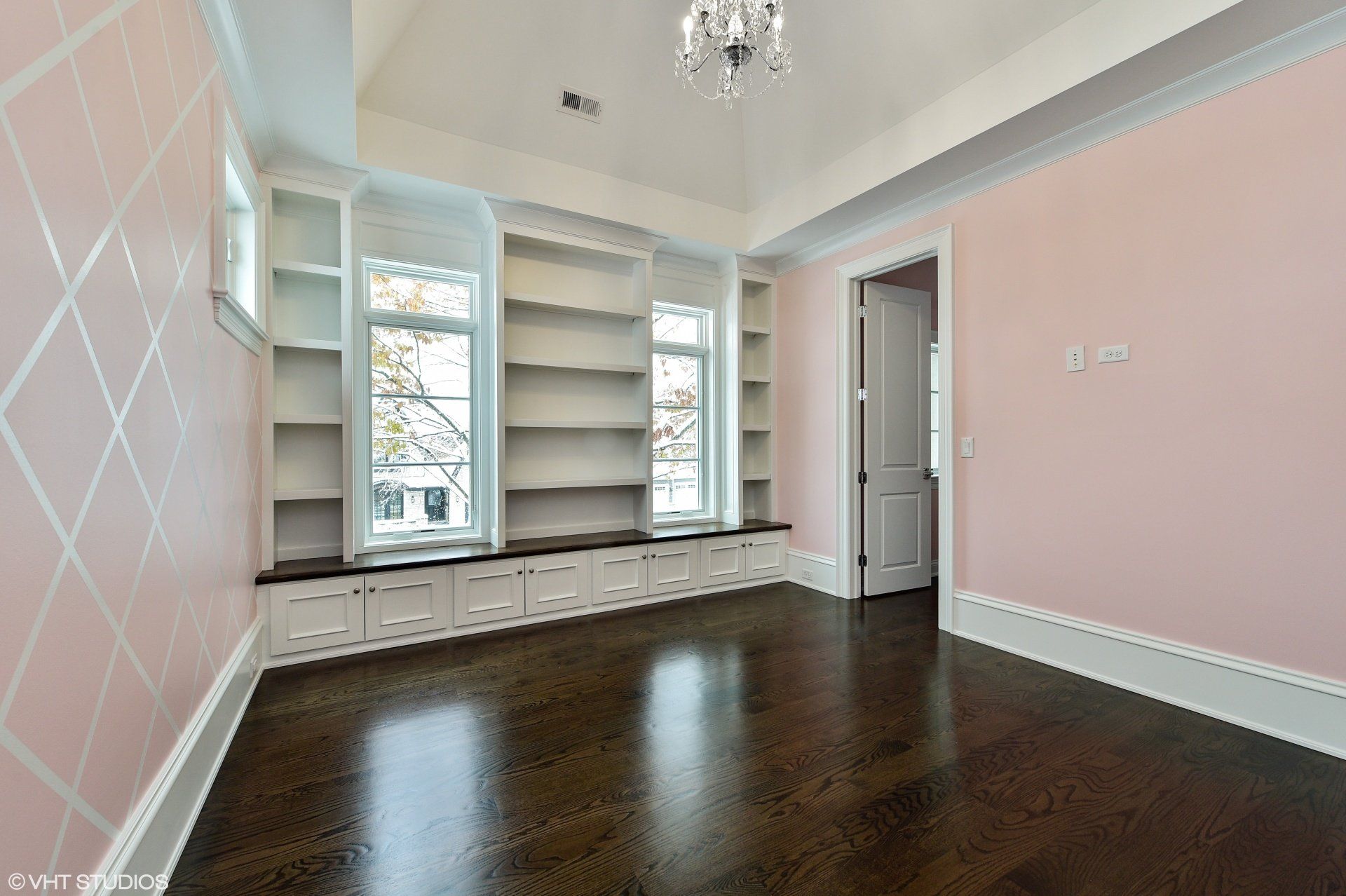 An empty room with pink walls and hardwood floors