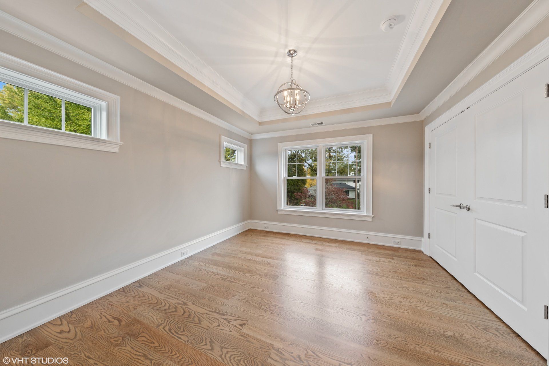 An empty room with hardwood floors and two windows.