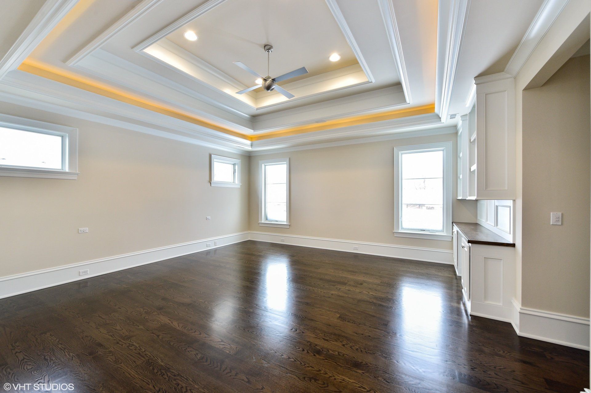 A large empty room with hardwood floors and a ceiling fan.