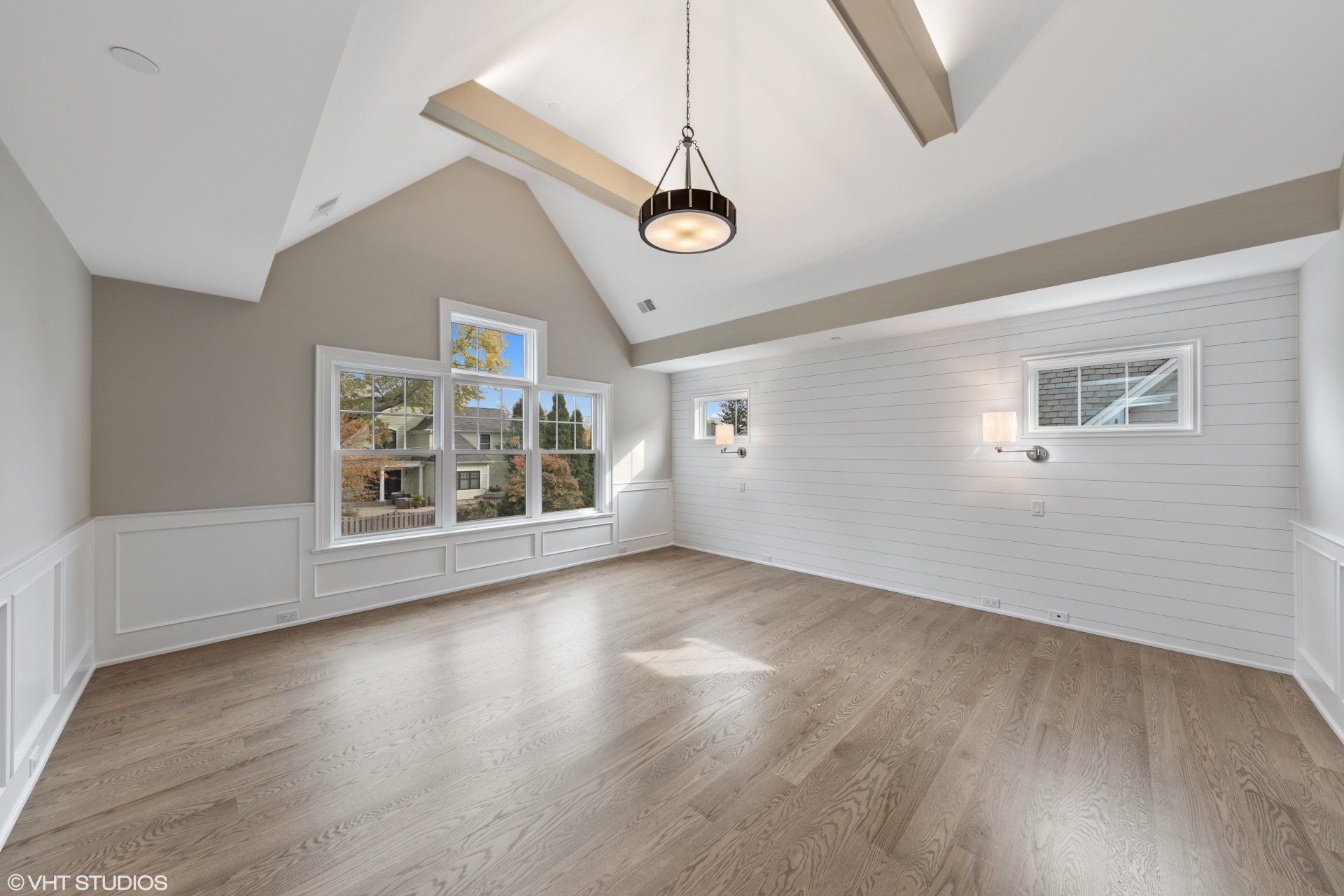 An empty living room with hardwood floors and a vaulted ceiling.