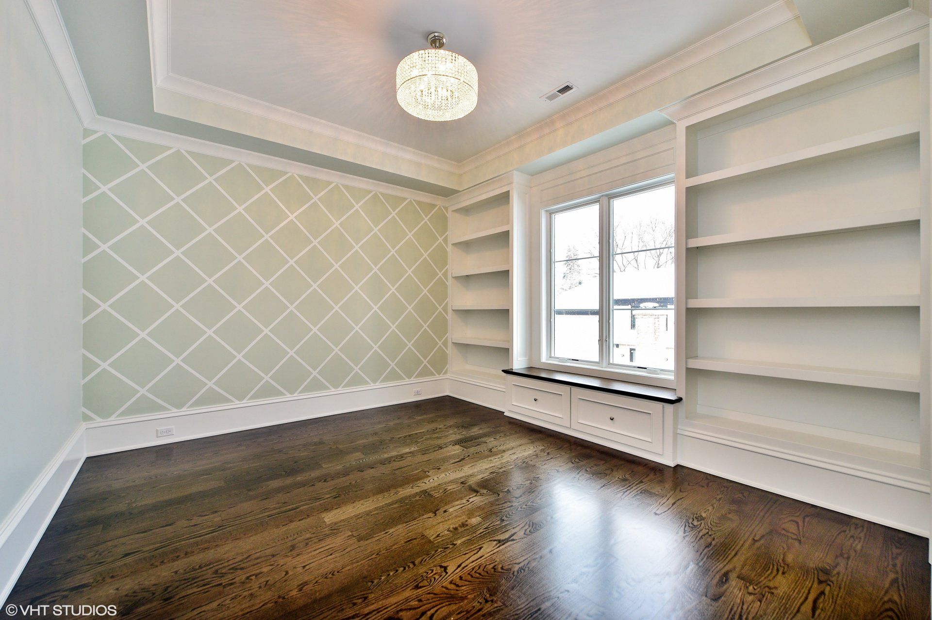 An empty room with hardwood floors and built in shelves