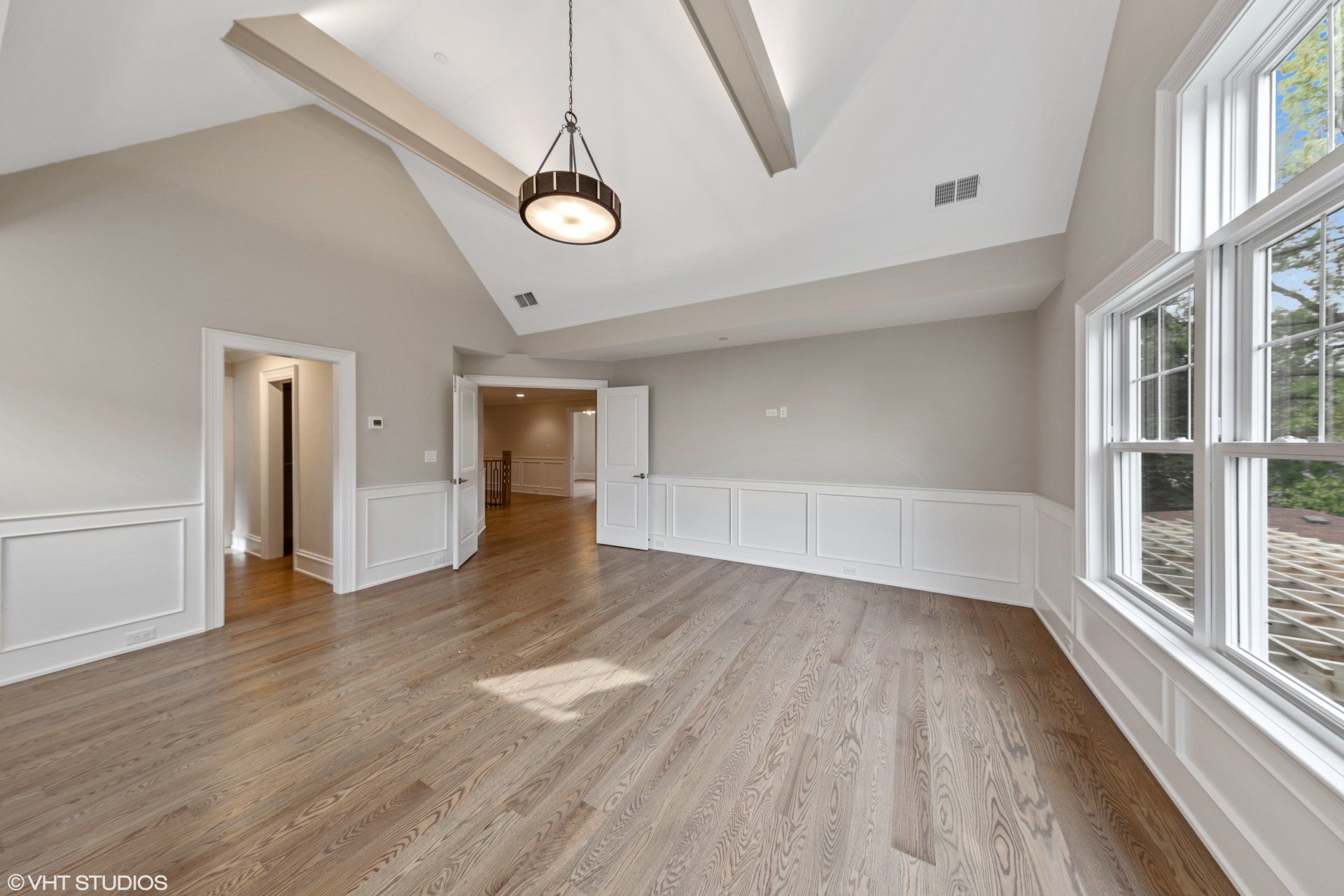 An empty living room with hardwood floors and a vaulted ceiling.