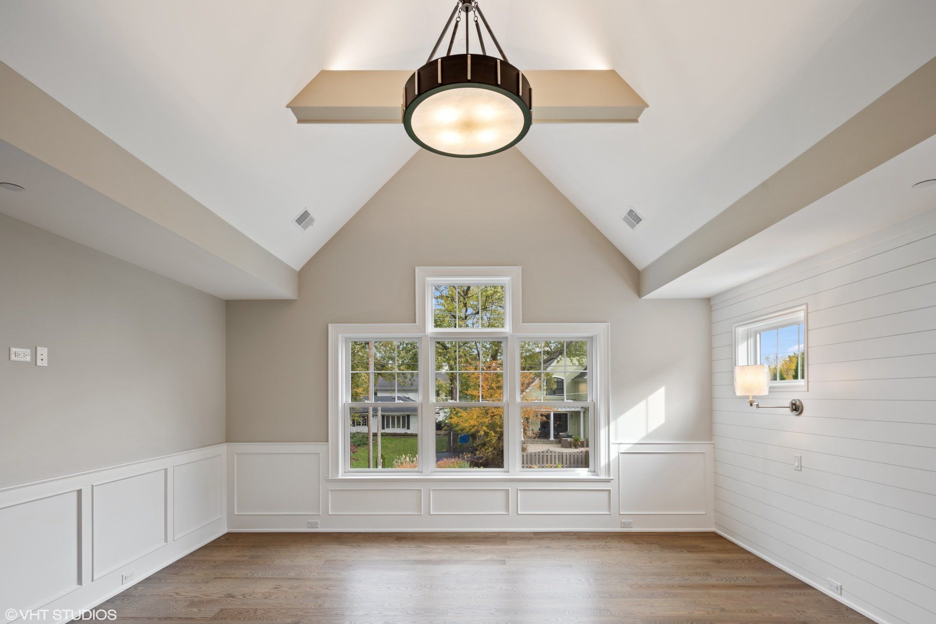 An empty room with a vaulted ceiling and a chandelier
