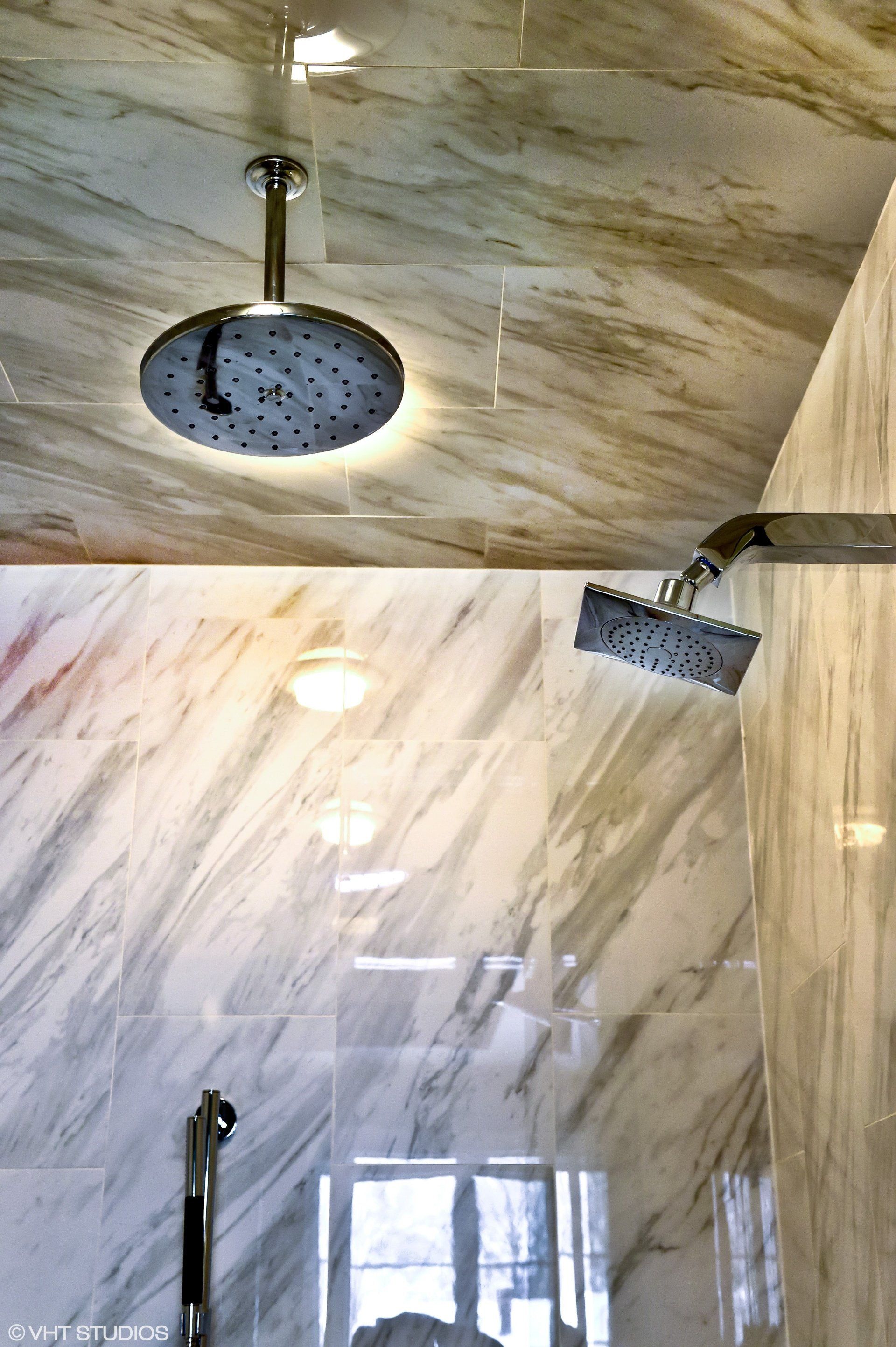 A shower head is hanging from the ceiling of a bathroom.