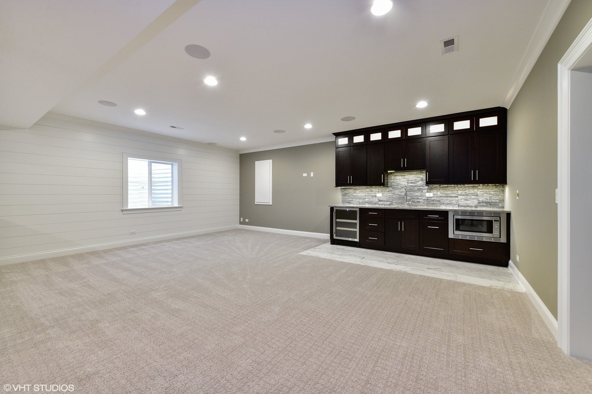 An empty basement with a kitchen and a window.