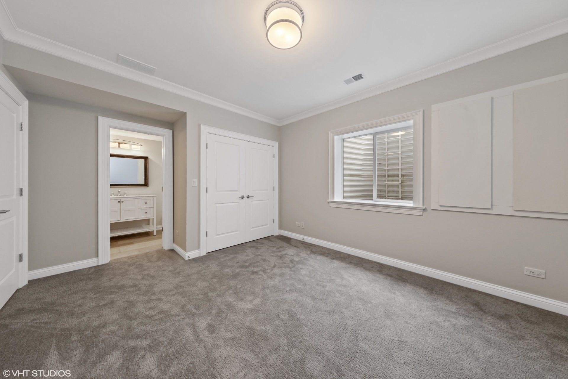 An empty bedroom with a carpeted floor and a window.