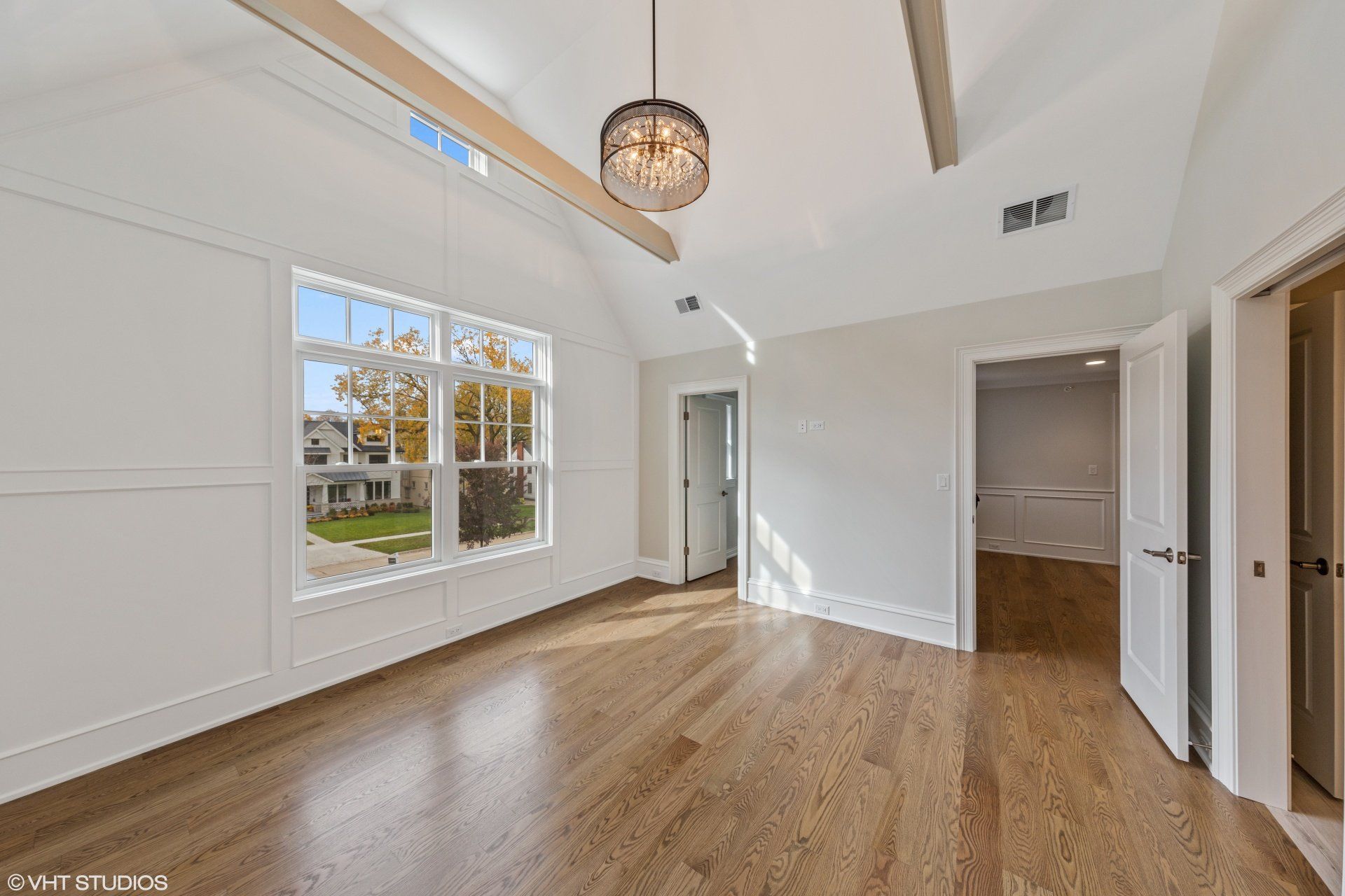 An empty bedroom with hardwood floors and a vaulted ceiling.