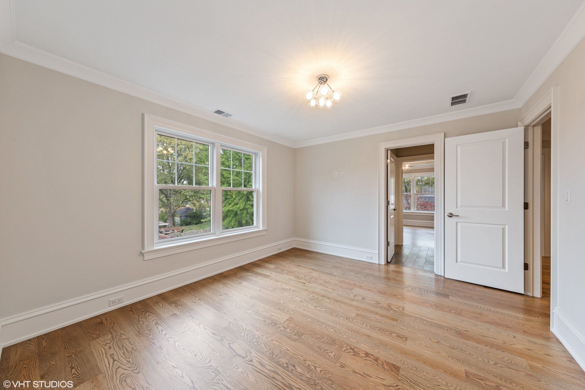 An empty bedroom with hardwood floors and two windows.