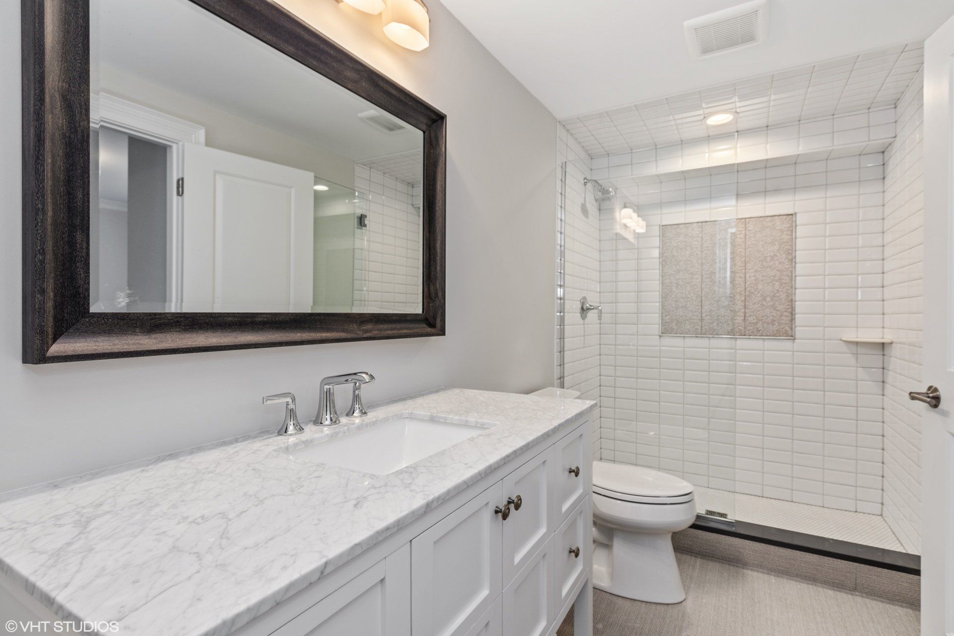 A bathroom with a sink , toilet , shower and mirror.