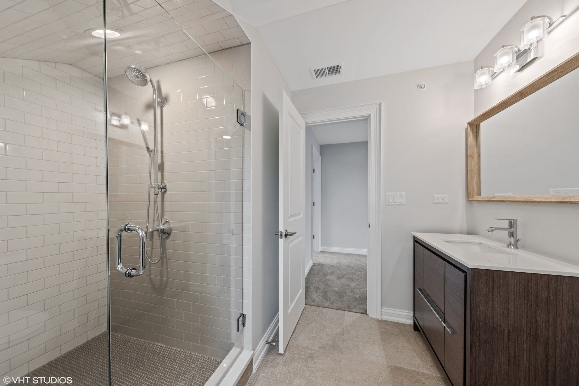 A bathroom with a walk in shower , sink and mirror.