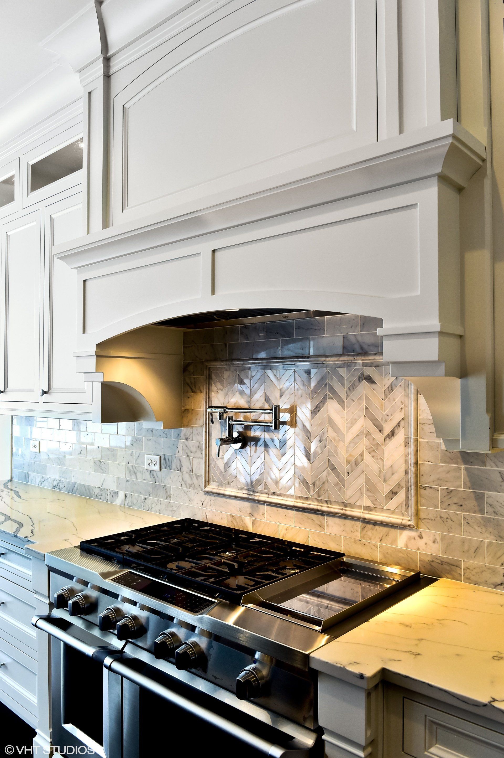 A kitchen with a stove top oven and a hood above it.