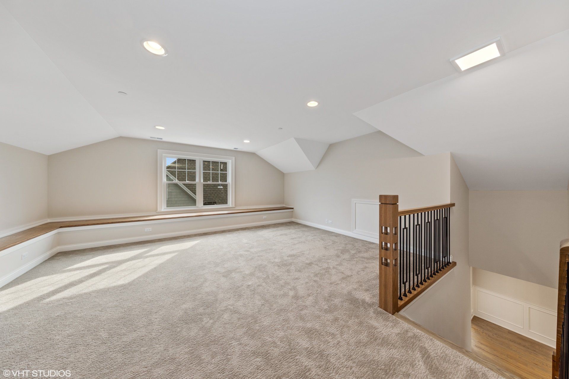 An empty attic with a staircase and a window.