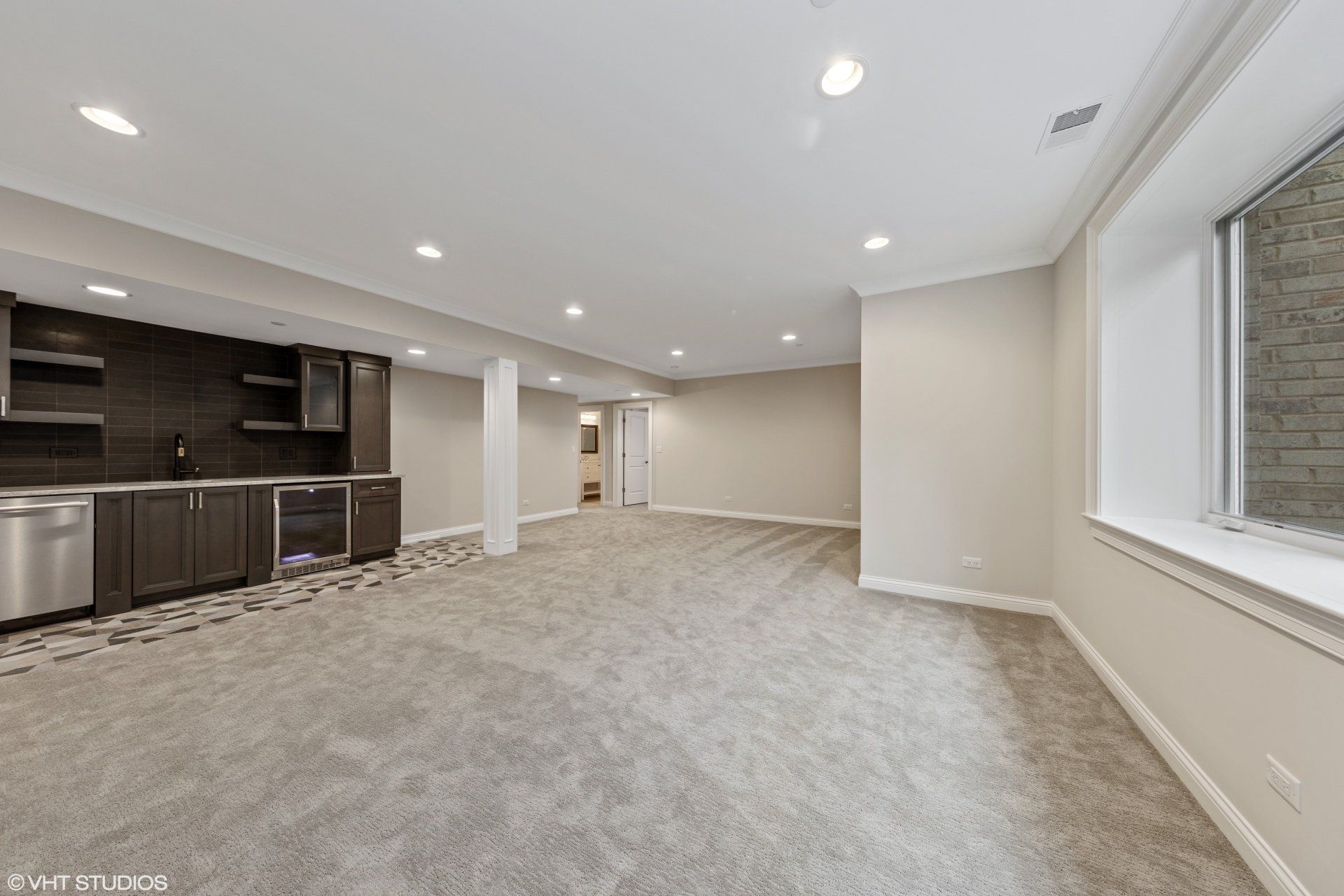 An empty basement with a kitchen and a window.