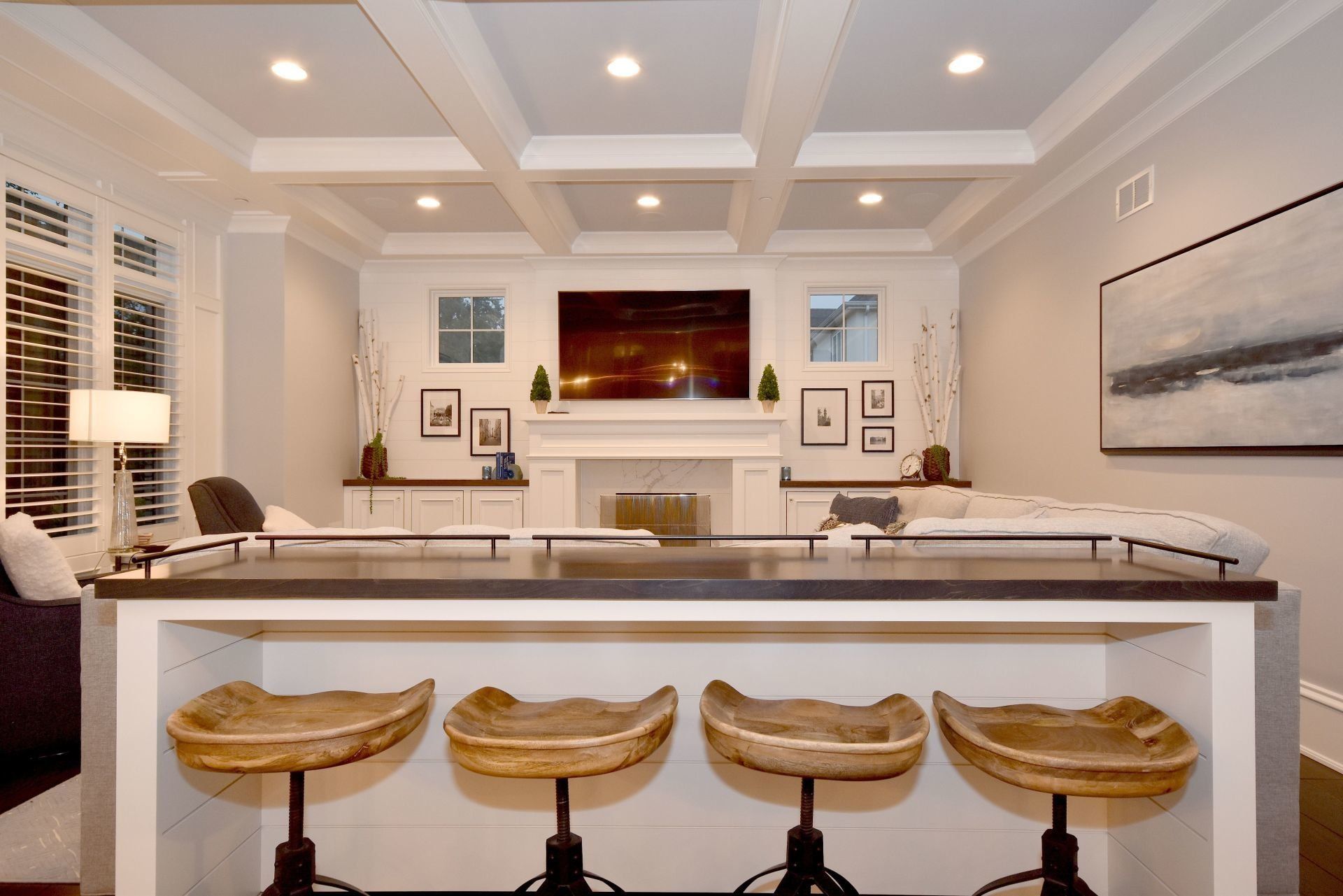 A living room with a bar and stools and a flat screen tv