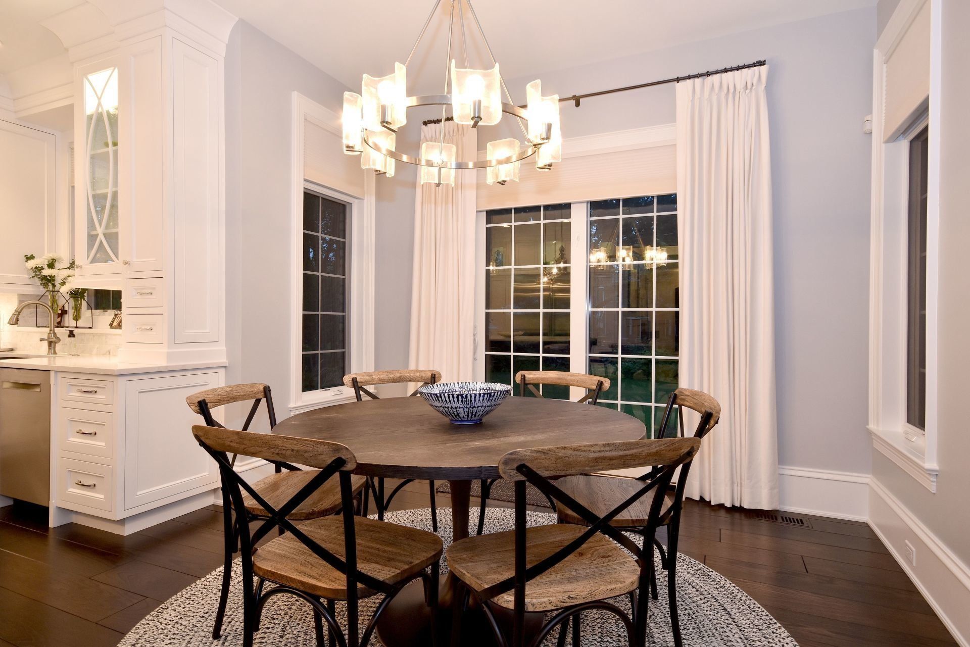 A dining room with a round table and chairs and a chandelier.