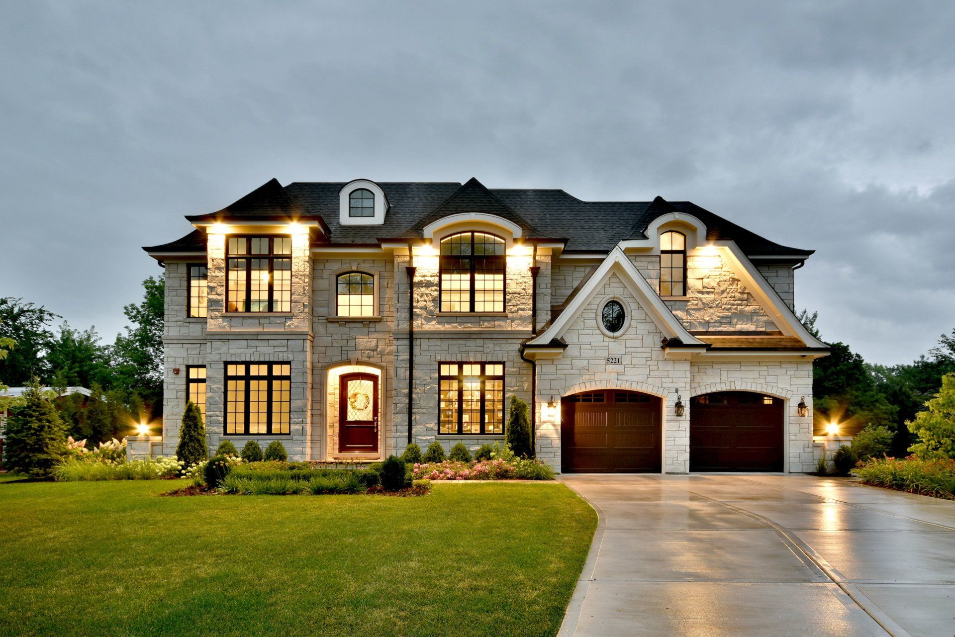 A large house with two garages is lit up at night.