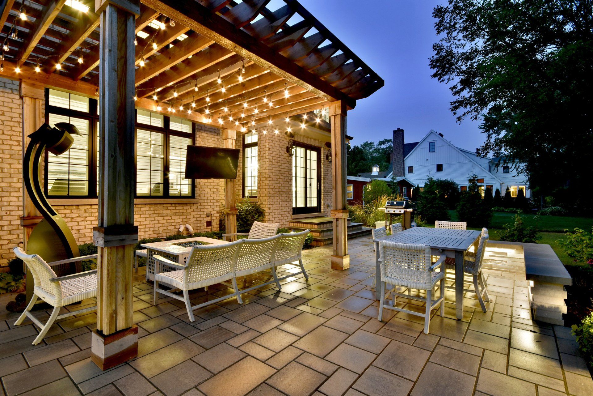 A patio with a table and chairs under a pergola at night.