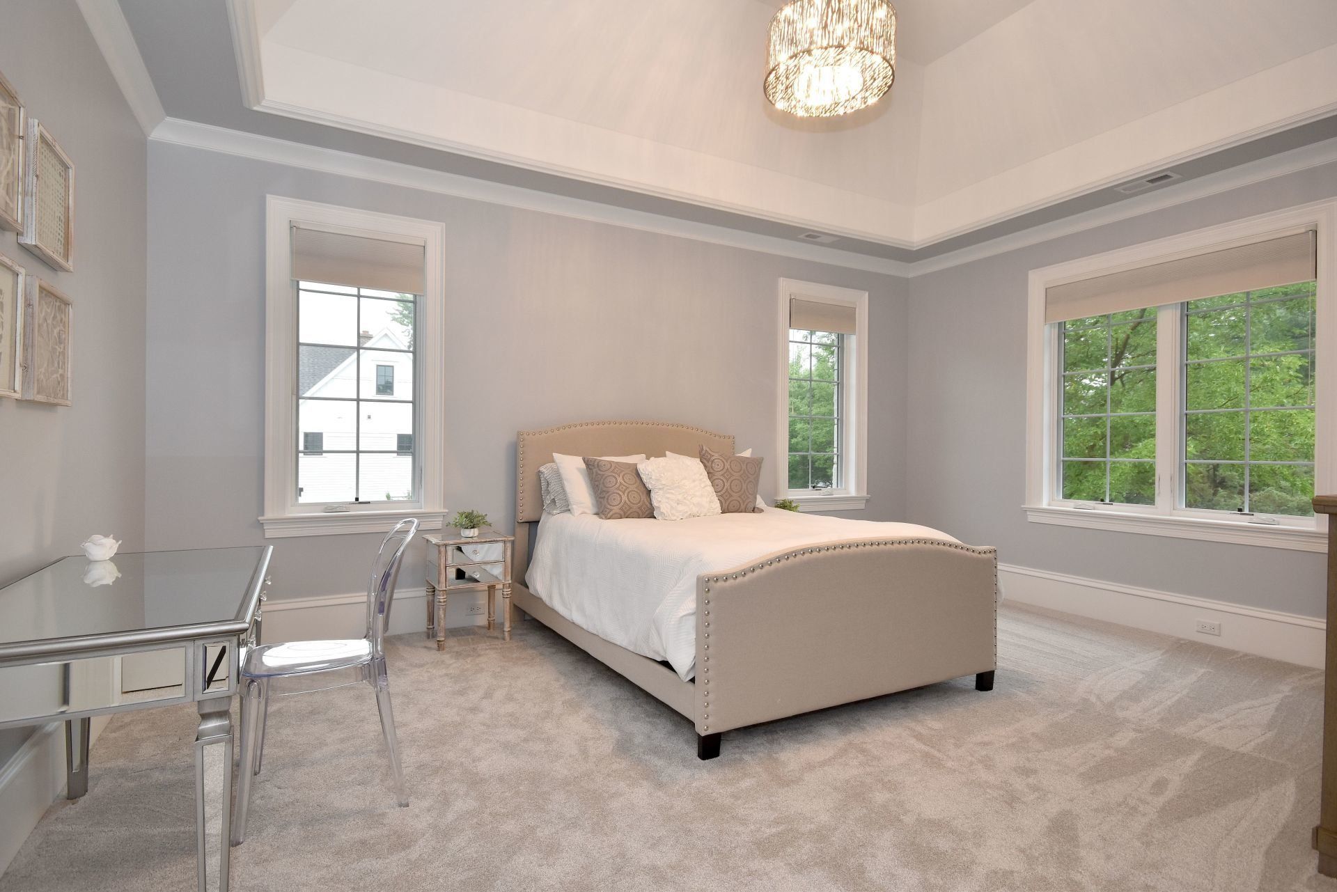 A bedroom with a bed , desk , chairs and windows.