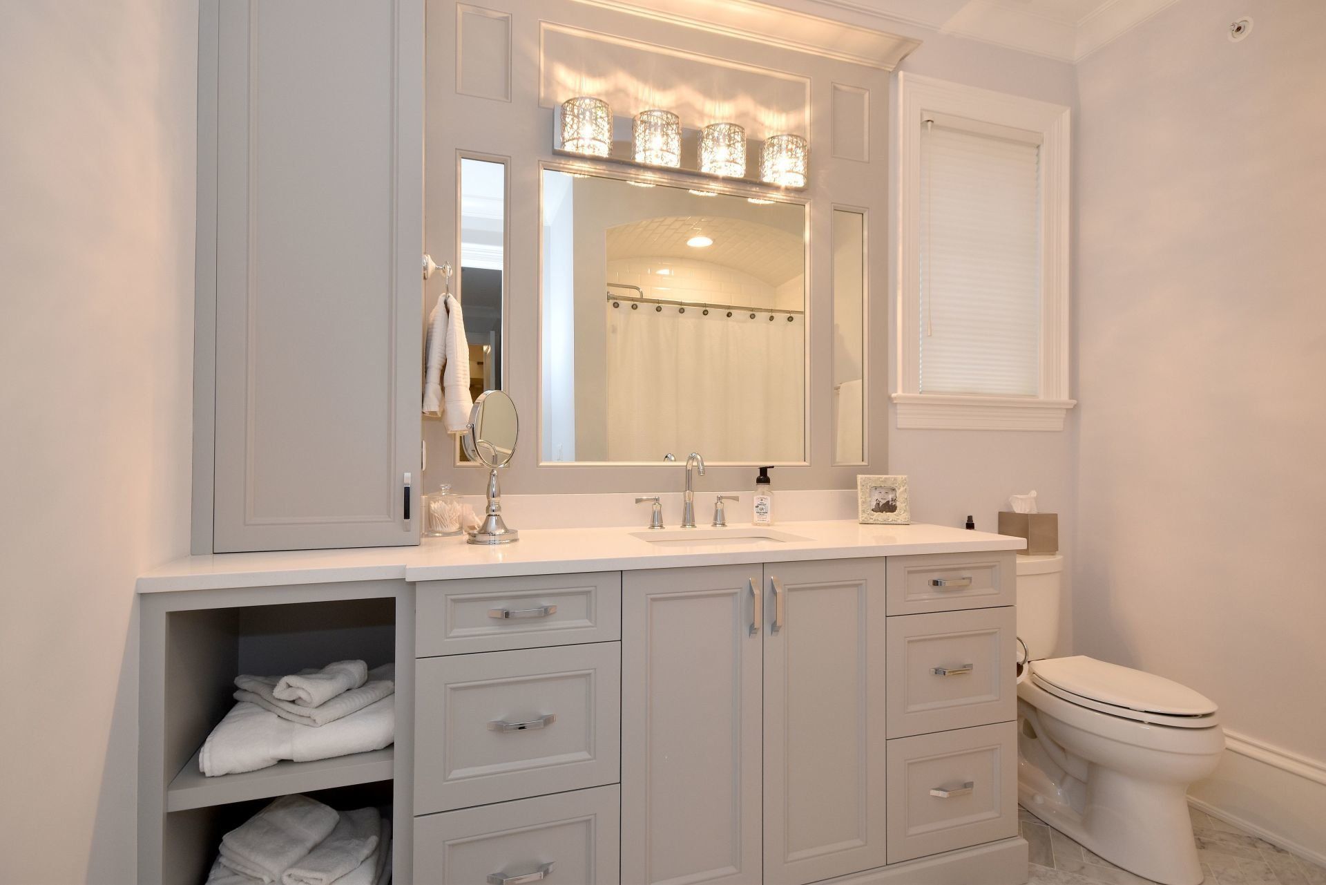 A bathroom with a toilet , sink , mirror and cabinets