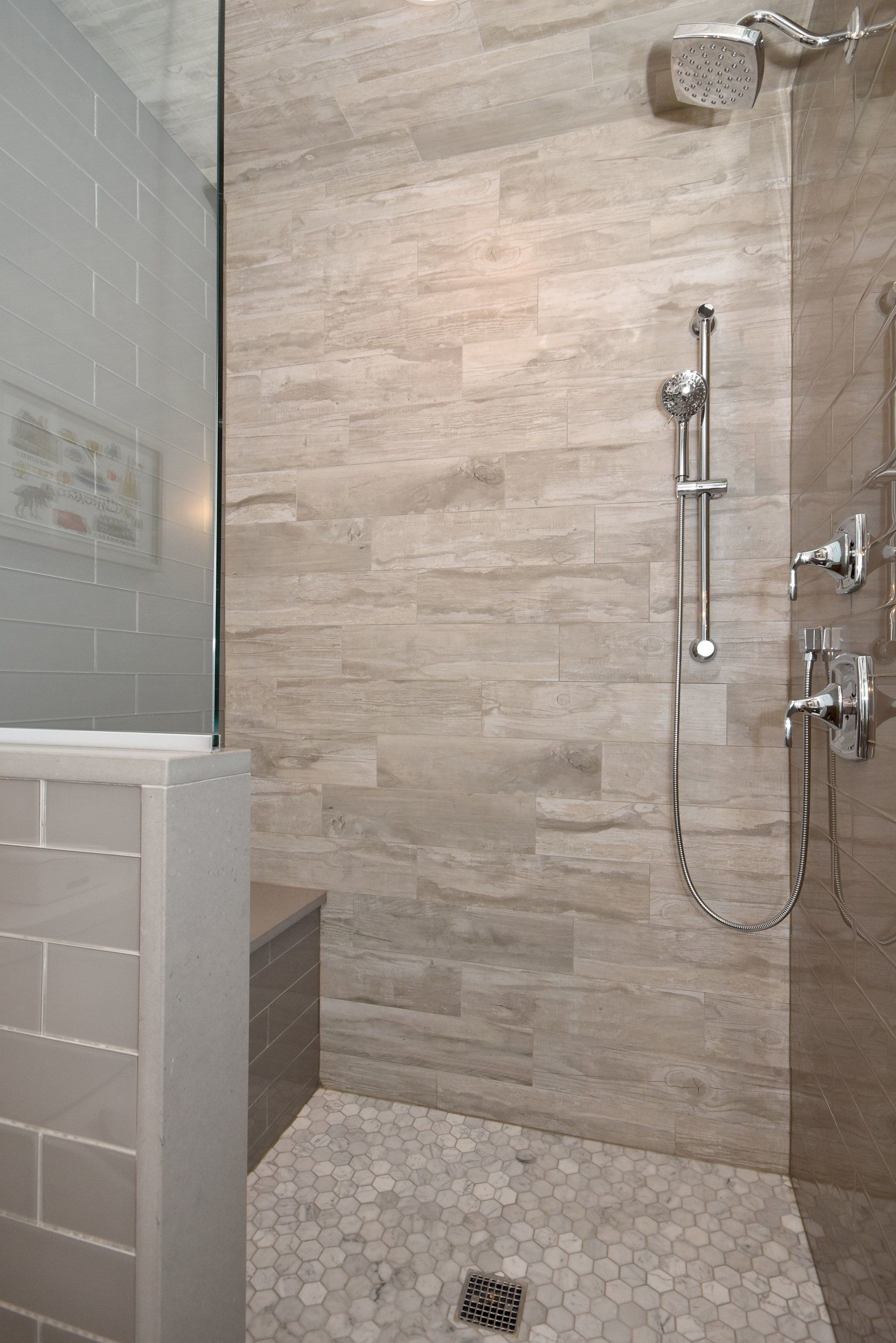 A bathroom with a walk in shower and a bench.
