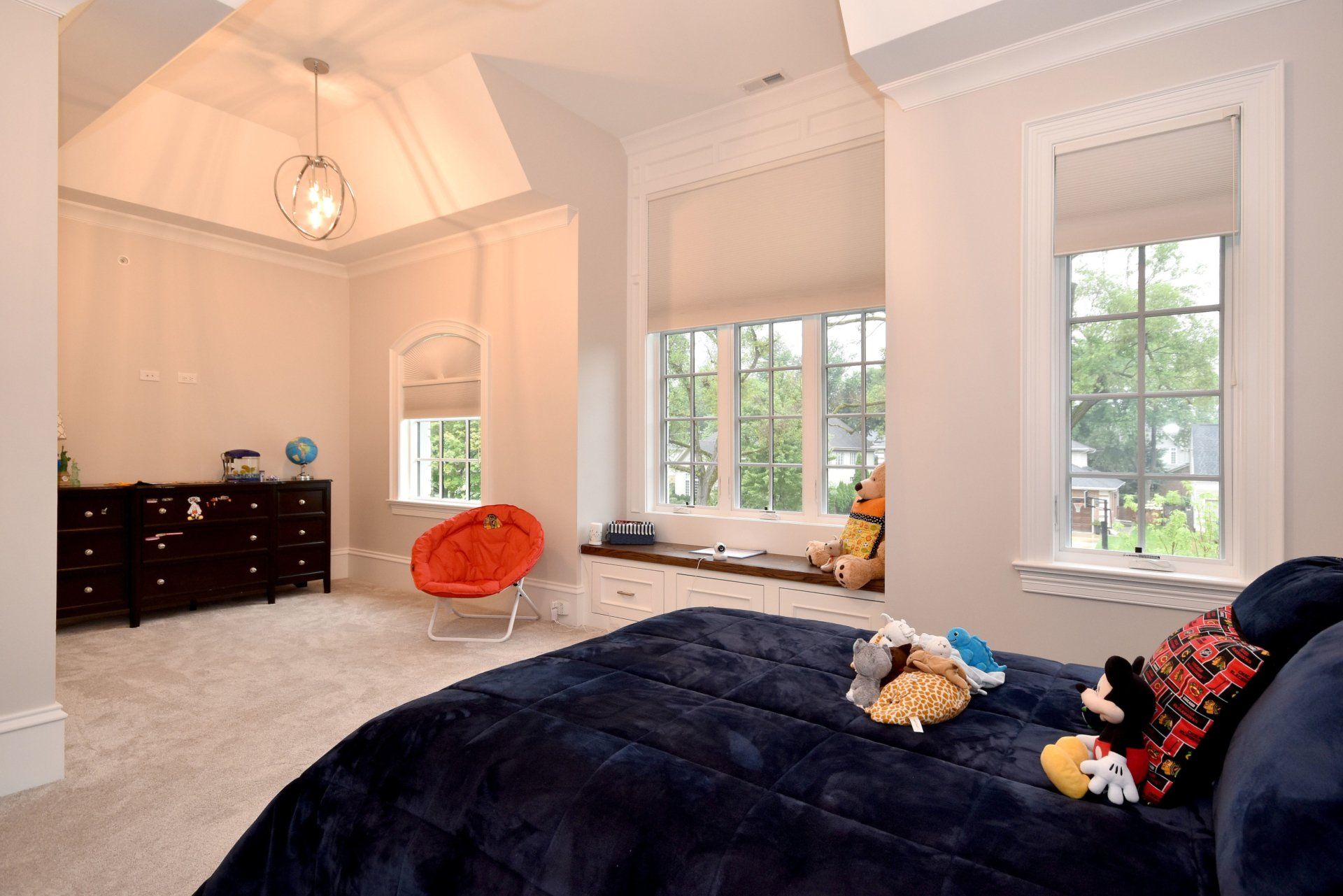 A bedroom with a bed , dresser , chair and two windows