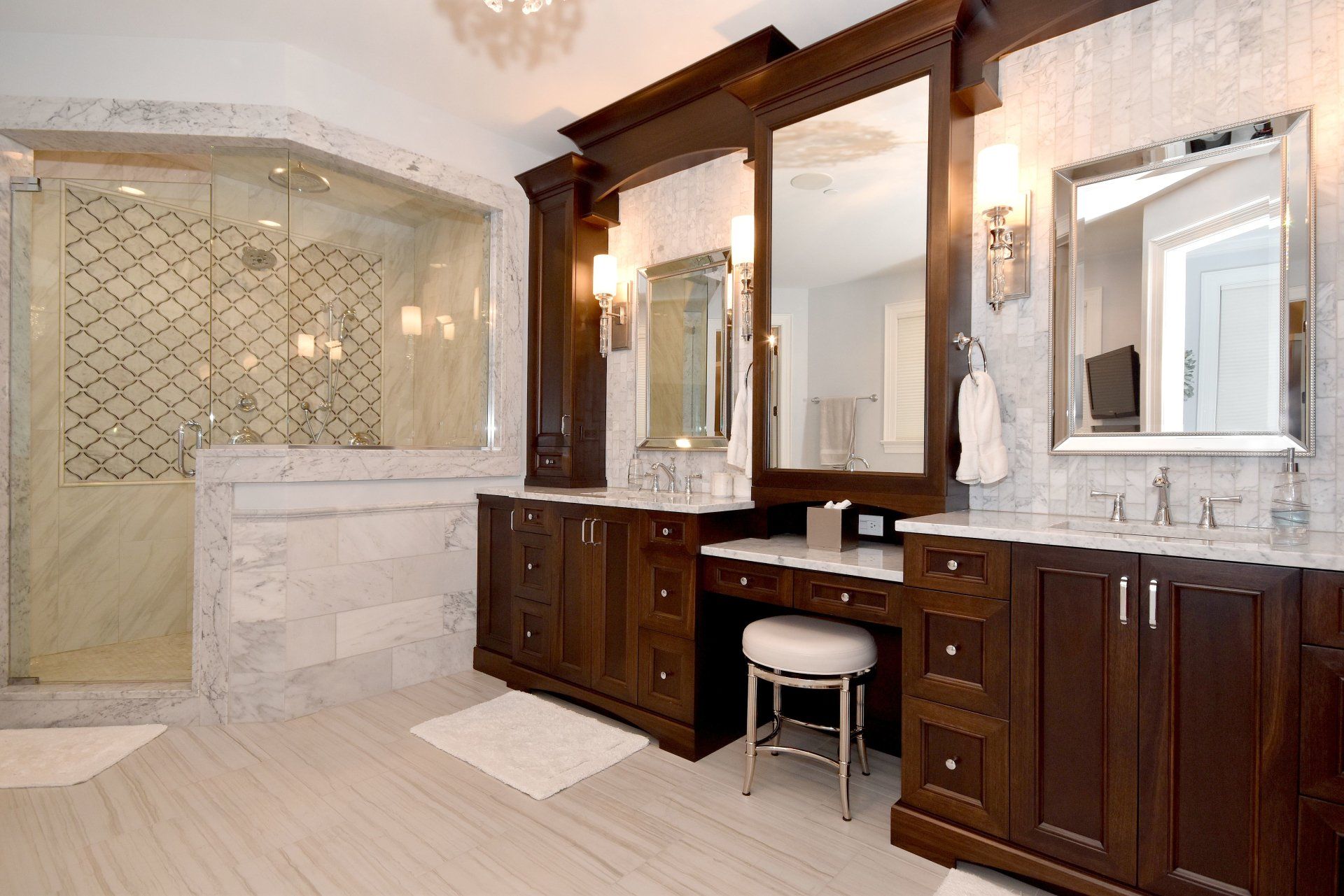 A bathroom with two sinks , two mirrors and a stool.