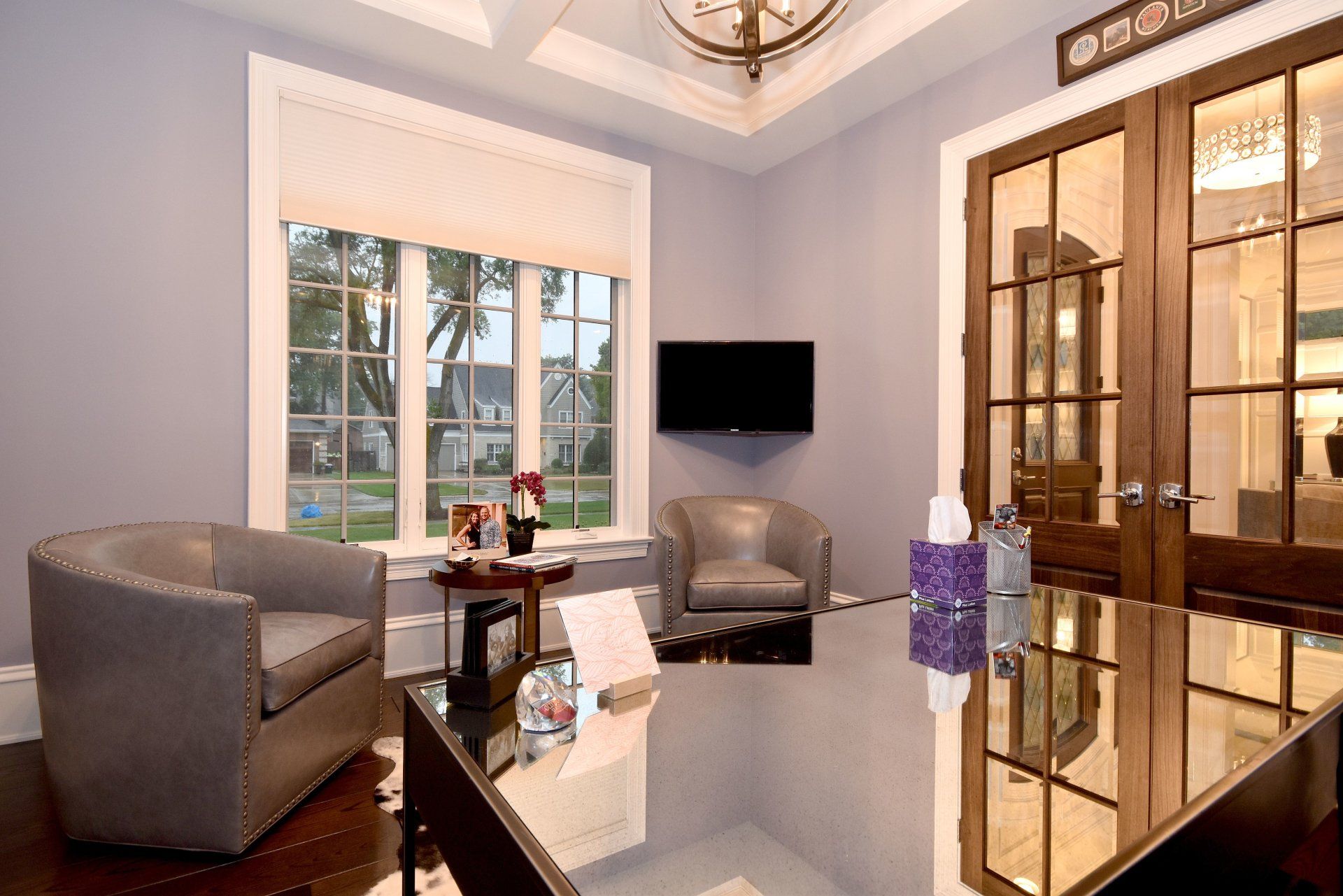 A living room with two chairs , a table , and a television.