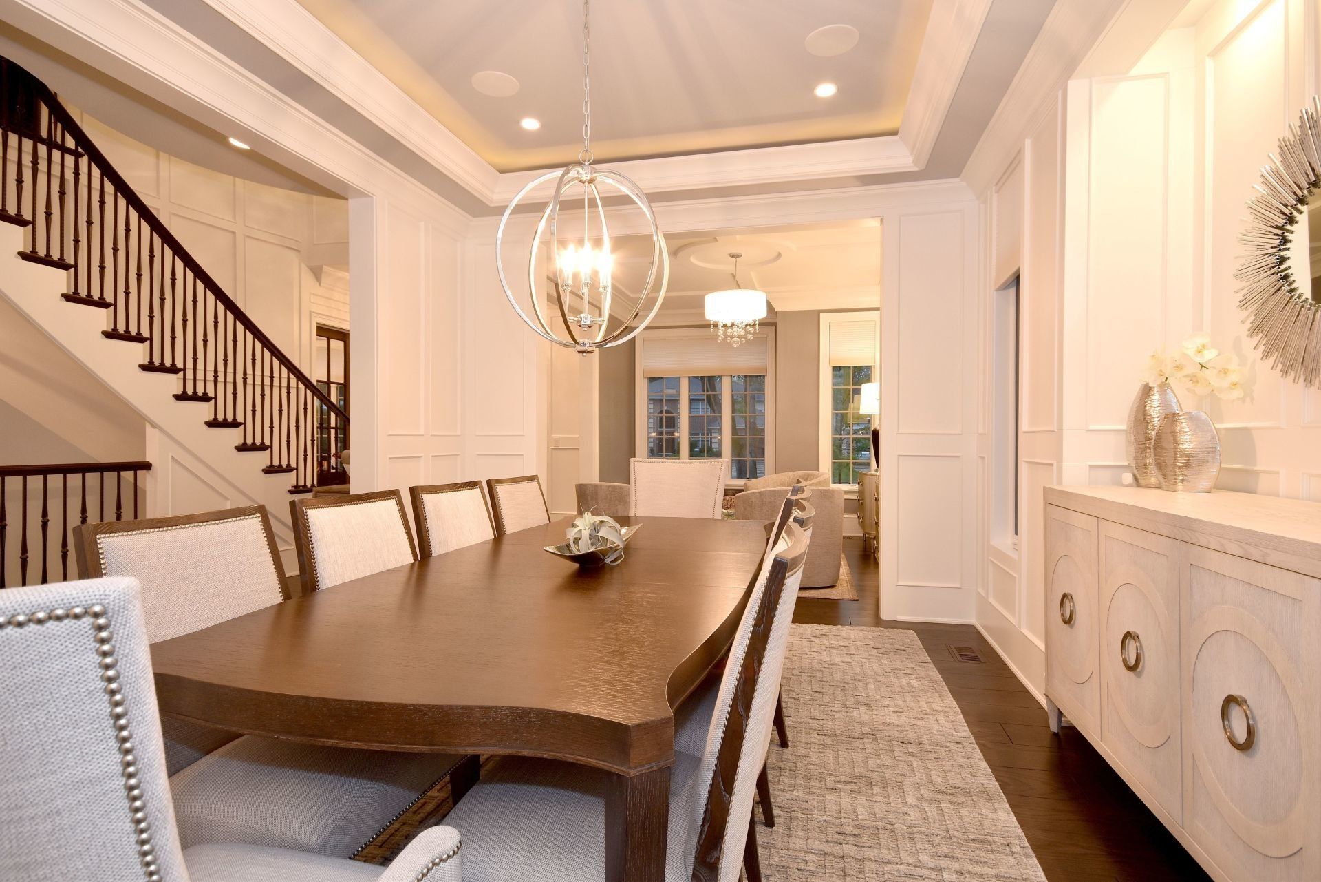 A dining room with a long table and chairs and a staircase.