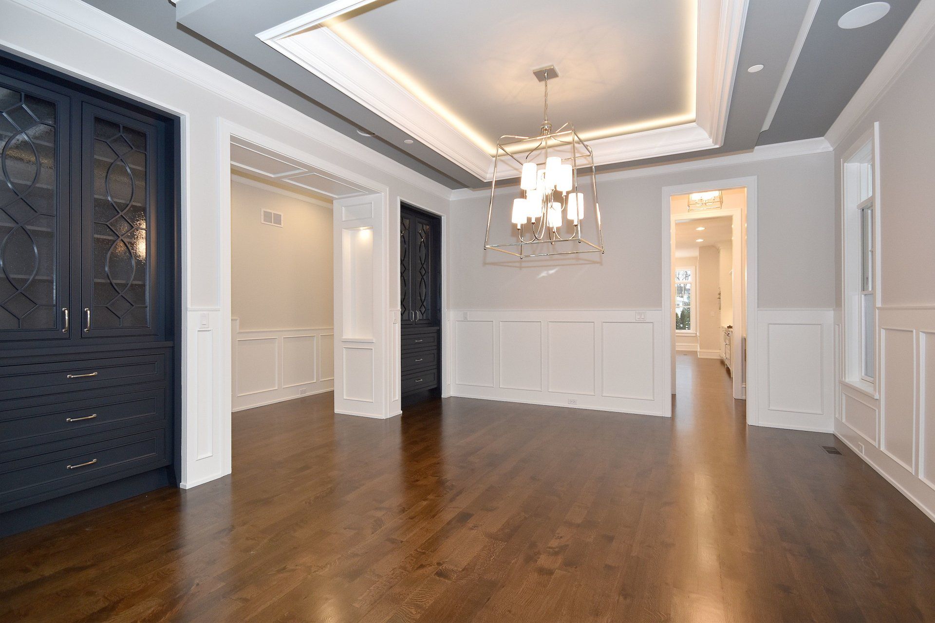 An empty dining room with hardwood floors and a chandelier.