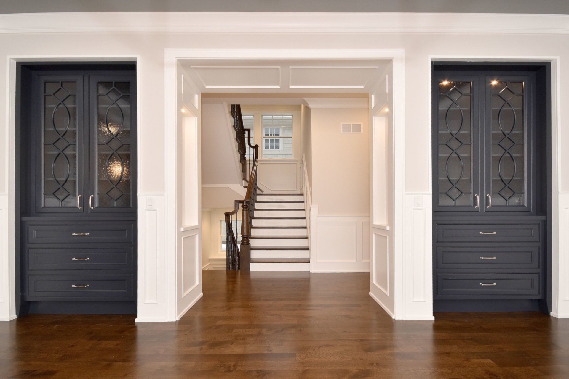 There is a staircase in the middle of the room between two cabinets.