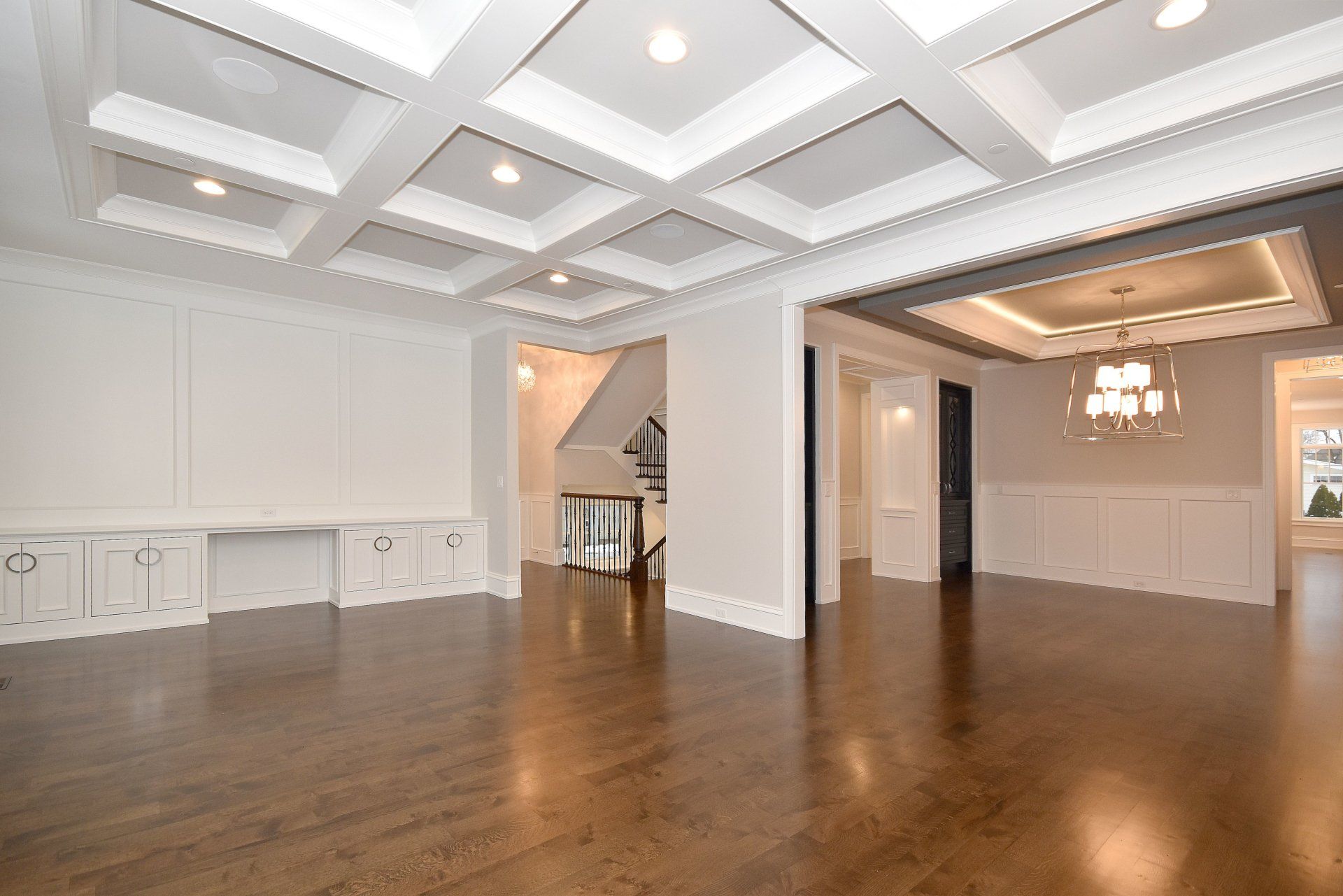 An empty living room with hardwood floors and a coffered ceiling.