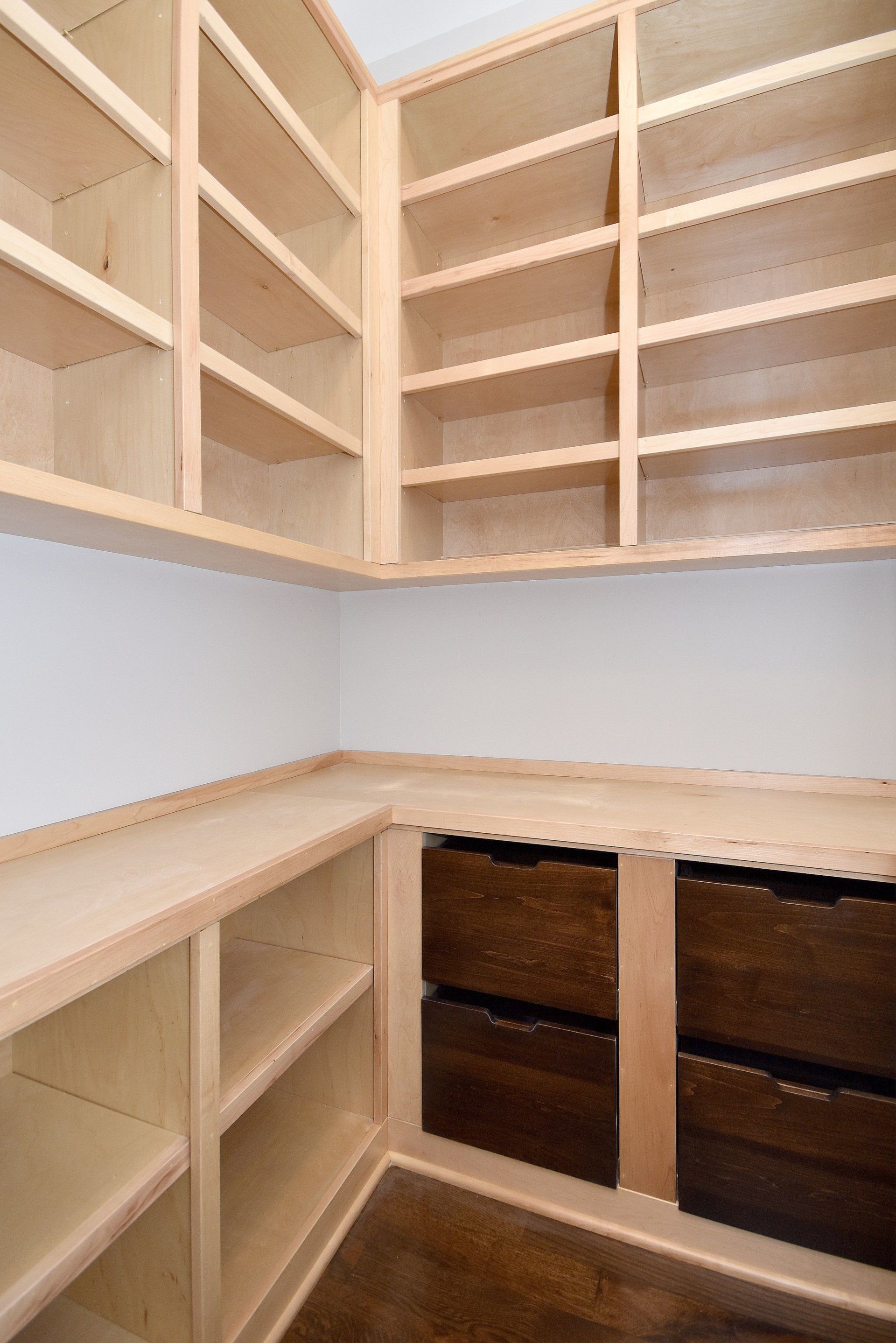 A corner of a room with wooden shelves and drawers
