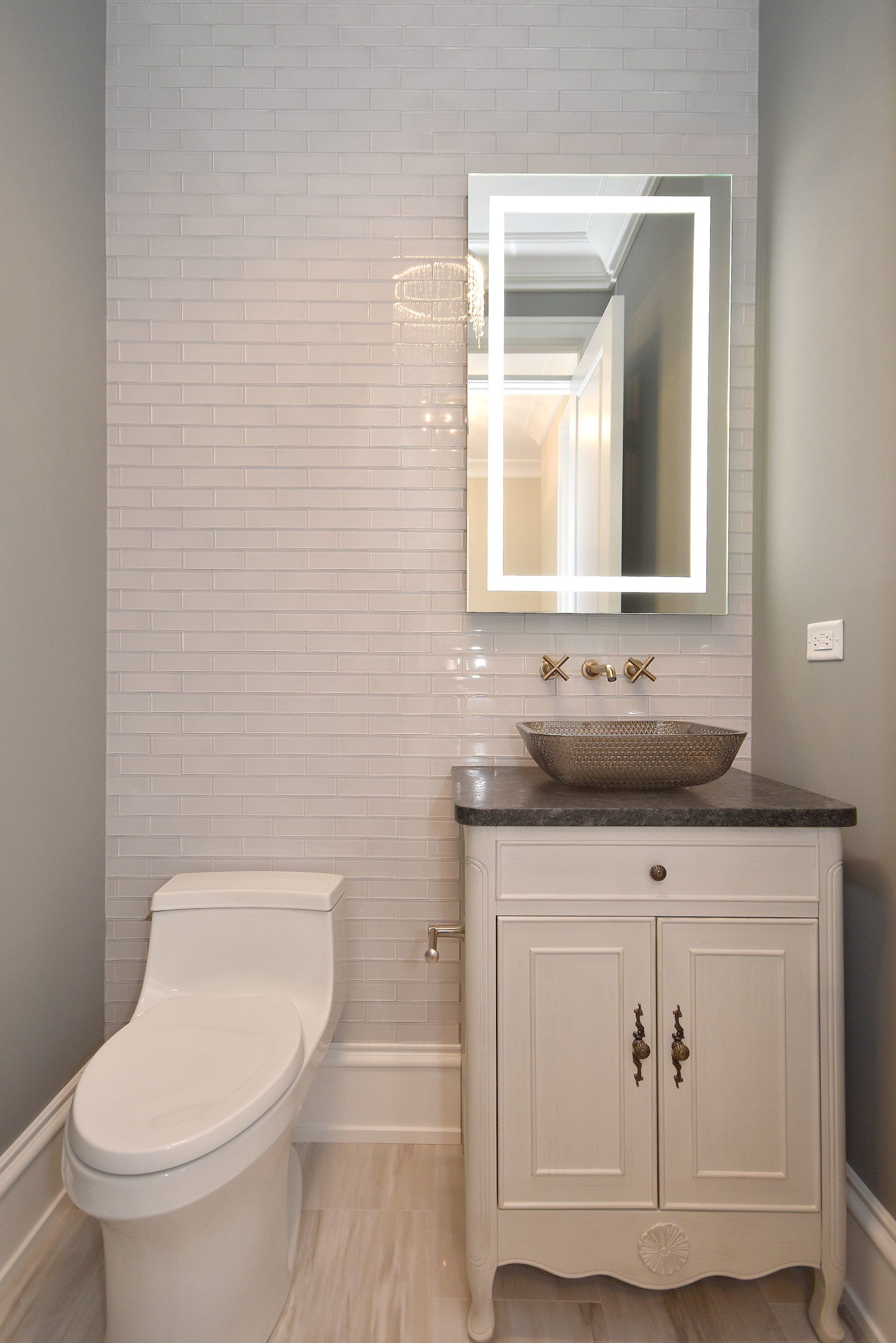 A bathroom with a toilet , sink and mirror.