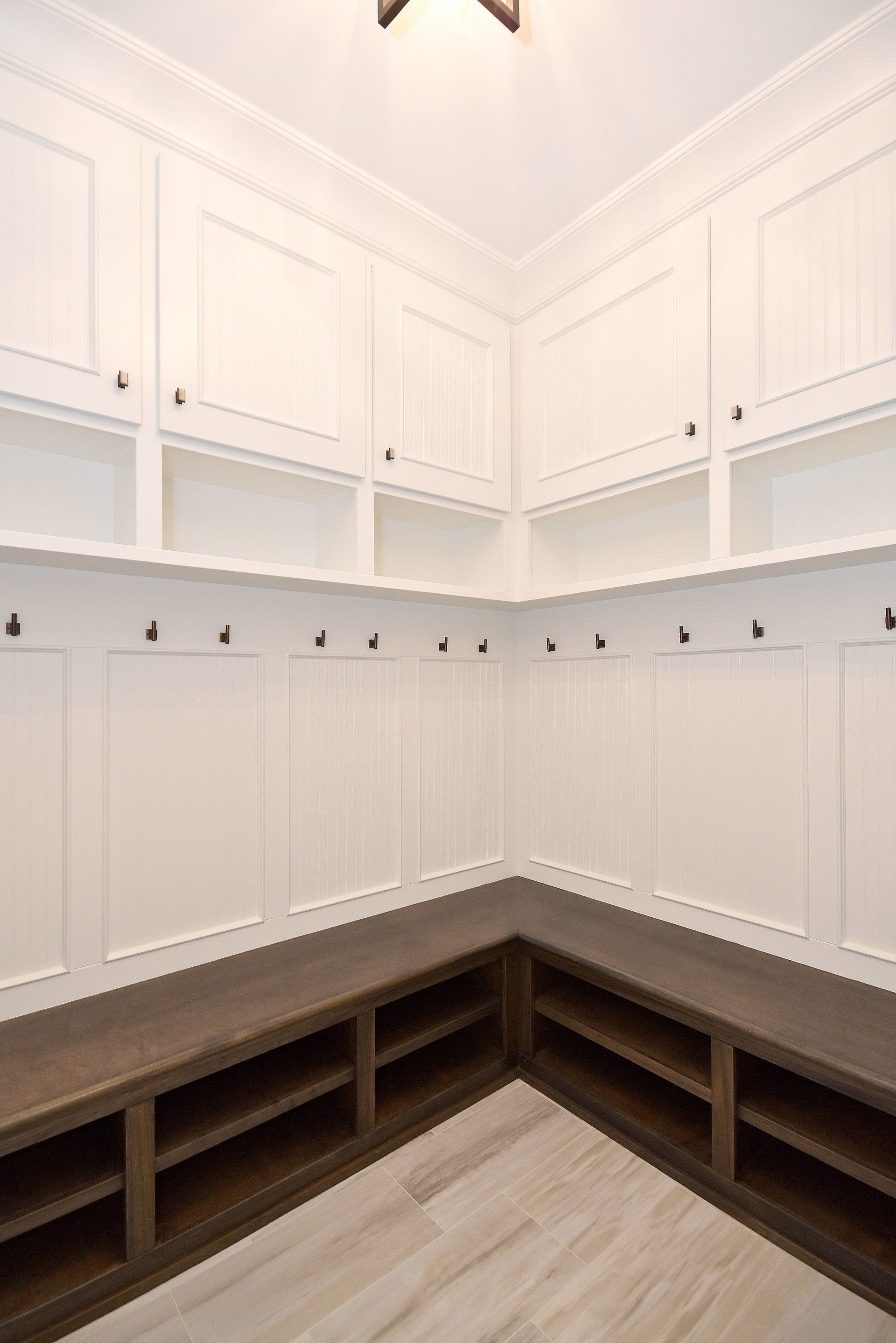 A mud room with white cabinets and a wooden bench.