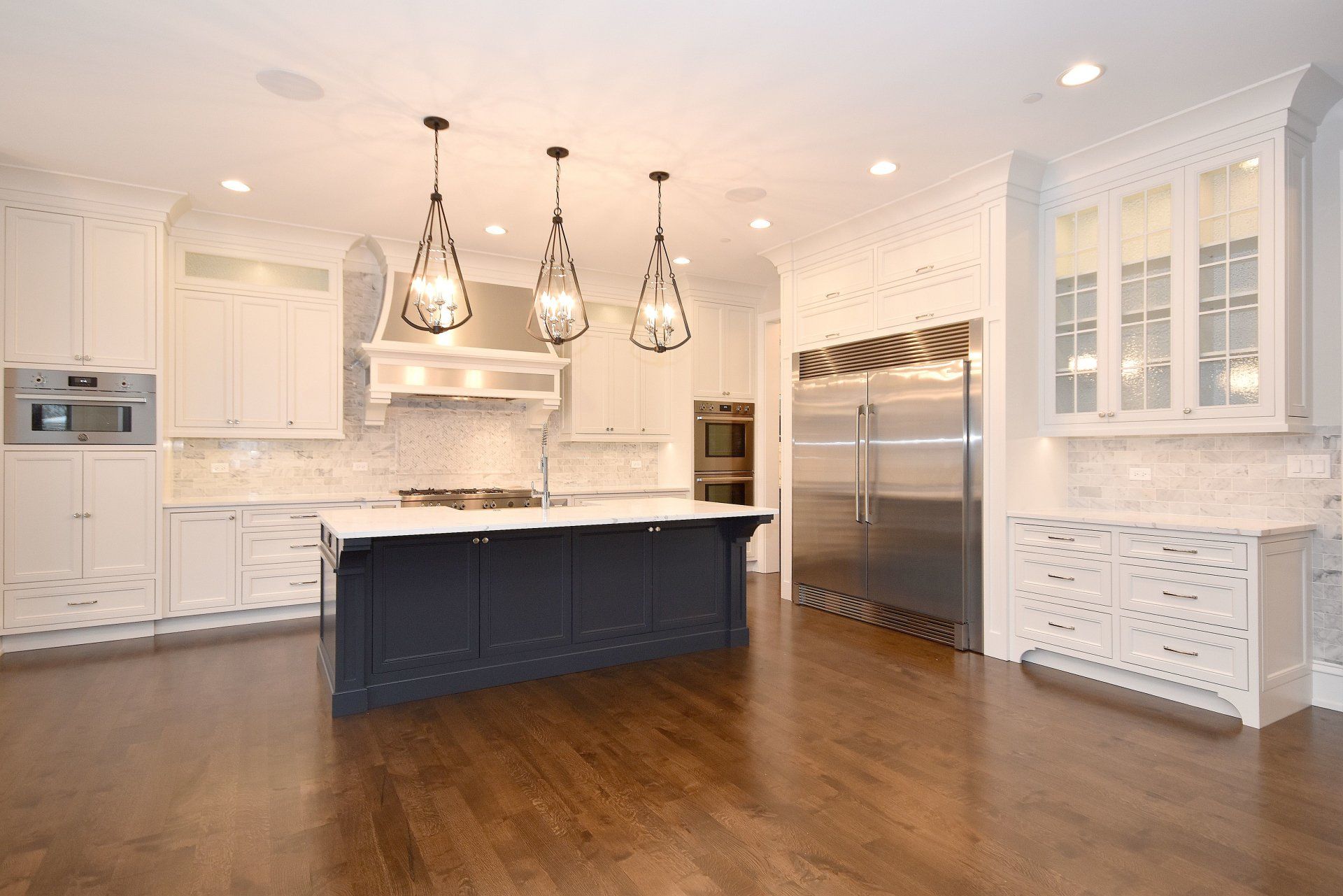 A kitchen with white cabinets and stainless steel appliances and a large island.
