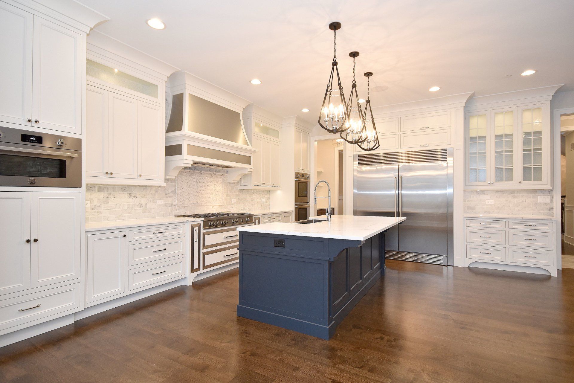 A kitchen with white cabinets , stainless steel appliances , and a large island.