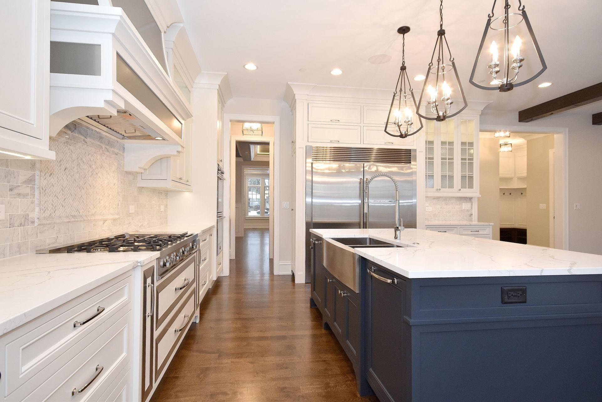 A kitchen with white cabinets , stainless steel appliances , and a large island.