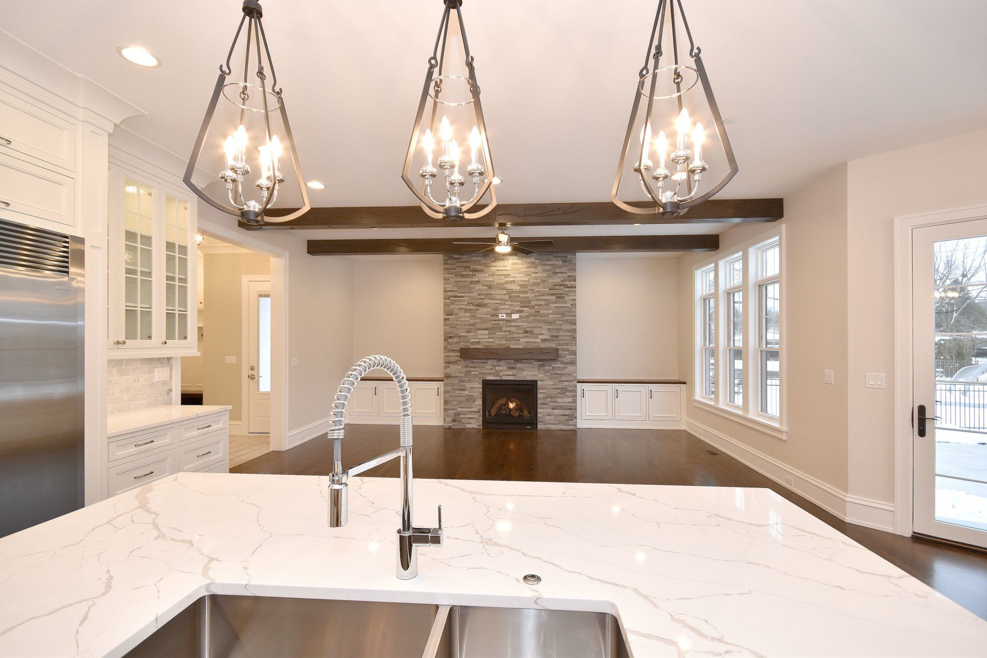 A kitchen with a sink and a fireplace in the background.