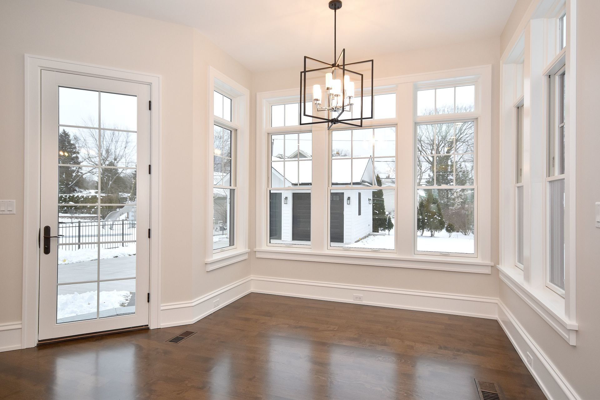 An empty room with a lot of windows and a chandelier hanging from the ceiling.