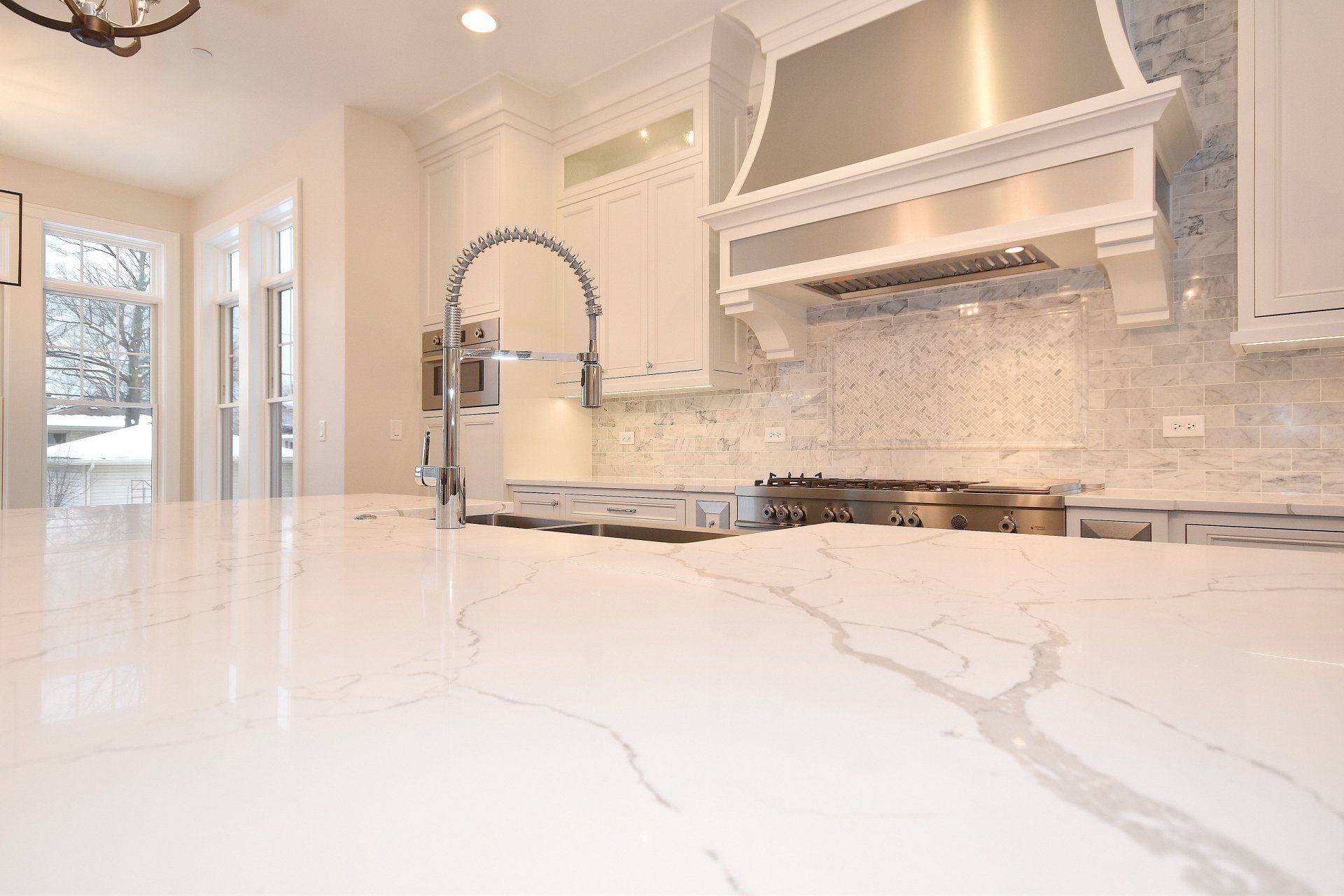 A kitchen with white cabinets , stainless steel appliances , and a marble counter top.