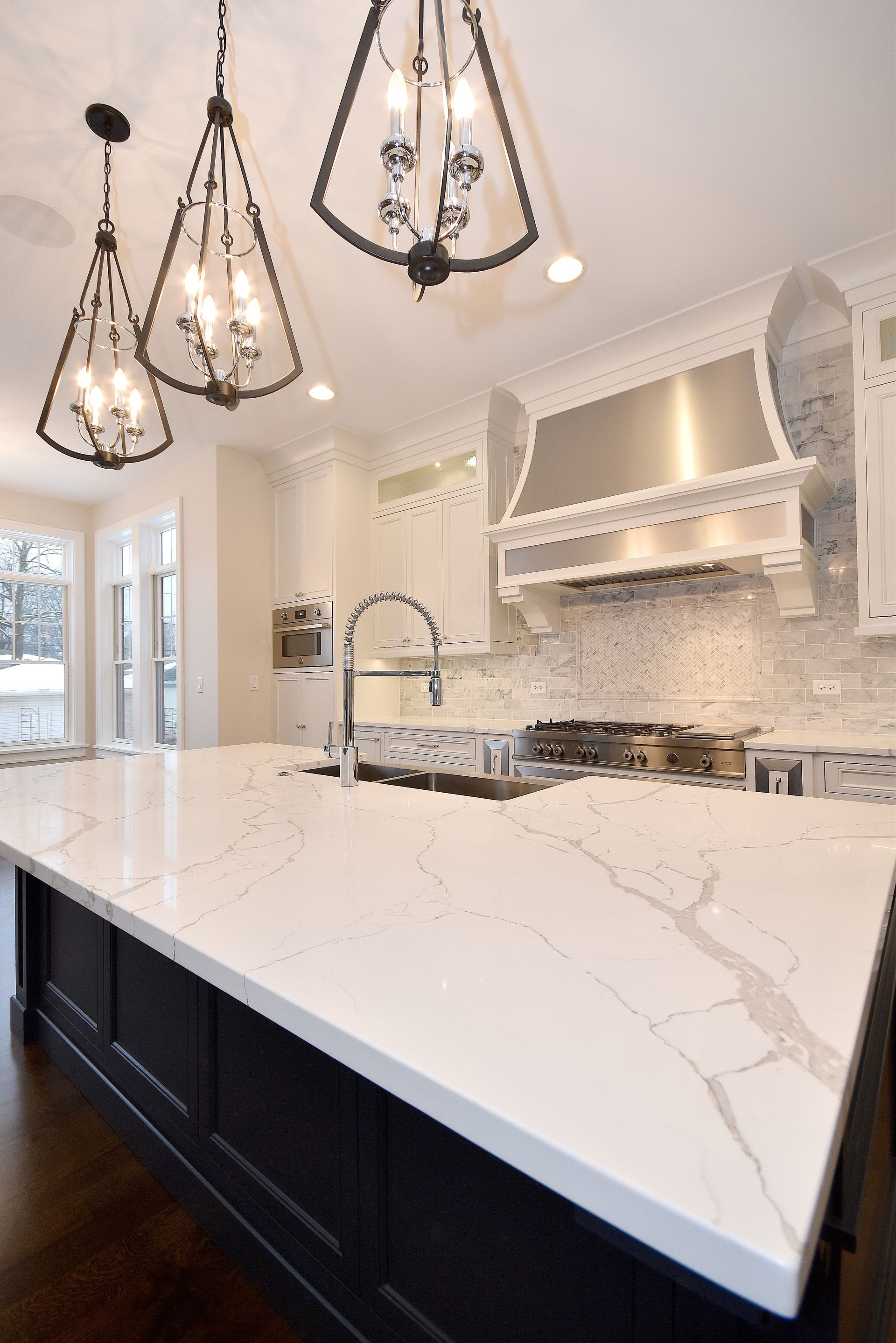 A kitchen with white counter tops , black cabinets , and stainless steel appliances.