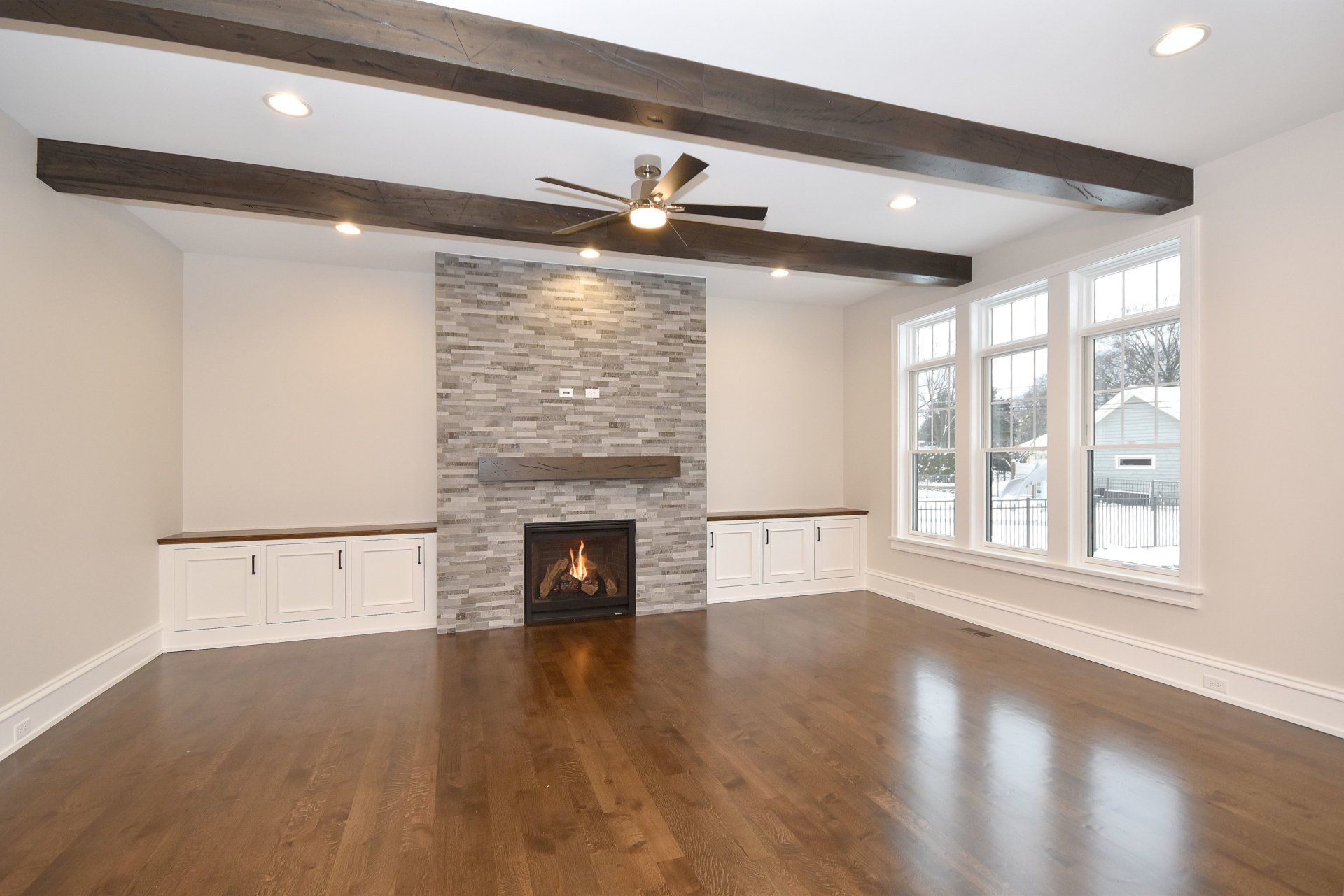 An empty living room with a fireplace and ceiling fan