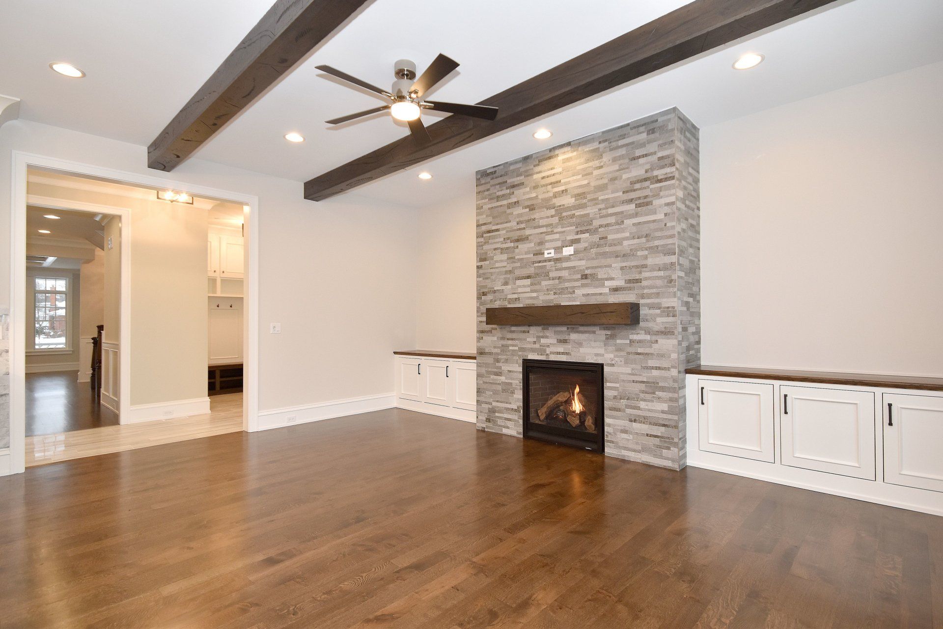An empty living room with a fireplace and a ceiling fan.