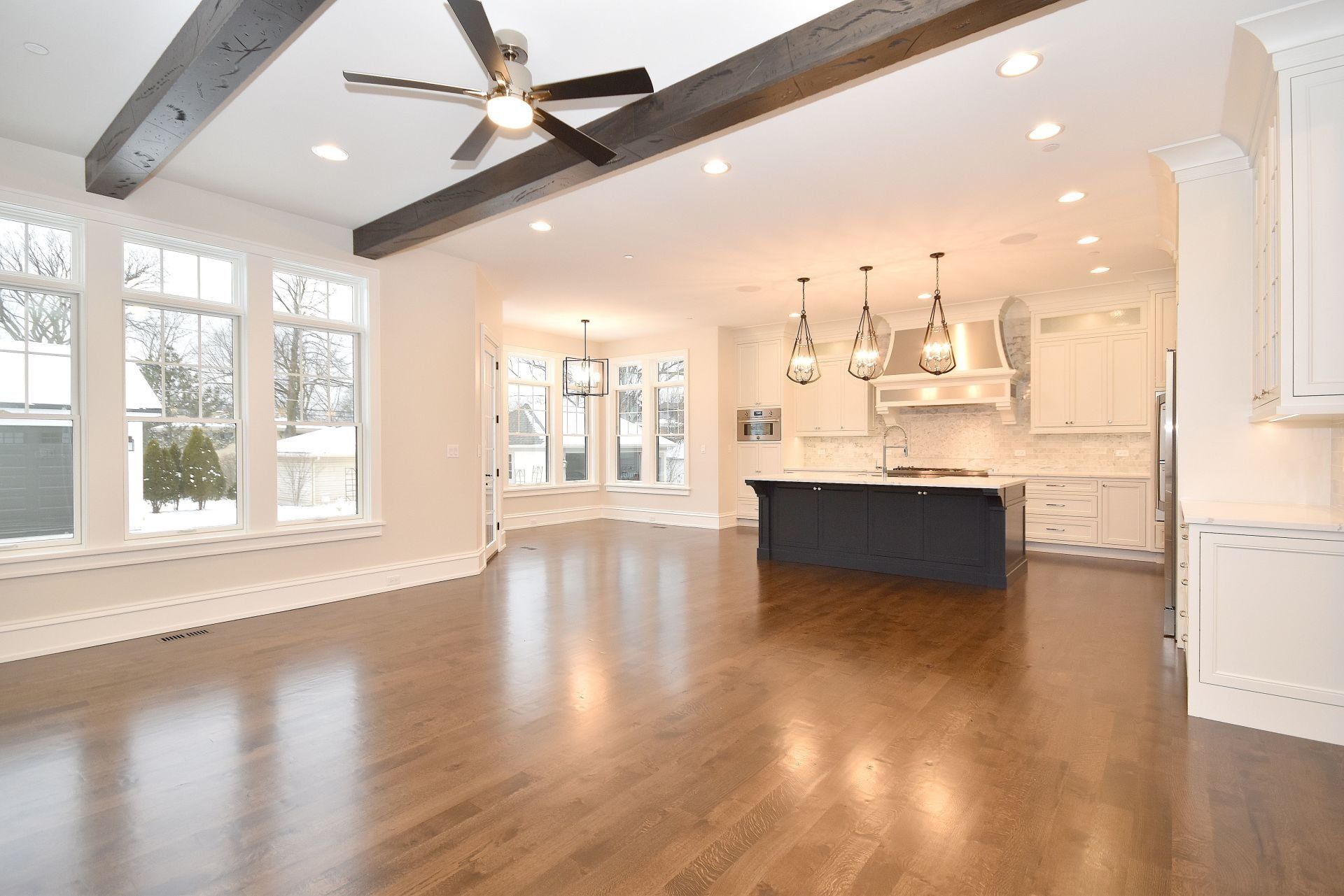 A large empty room with hardwood floors and a ceiling fan.