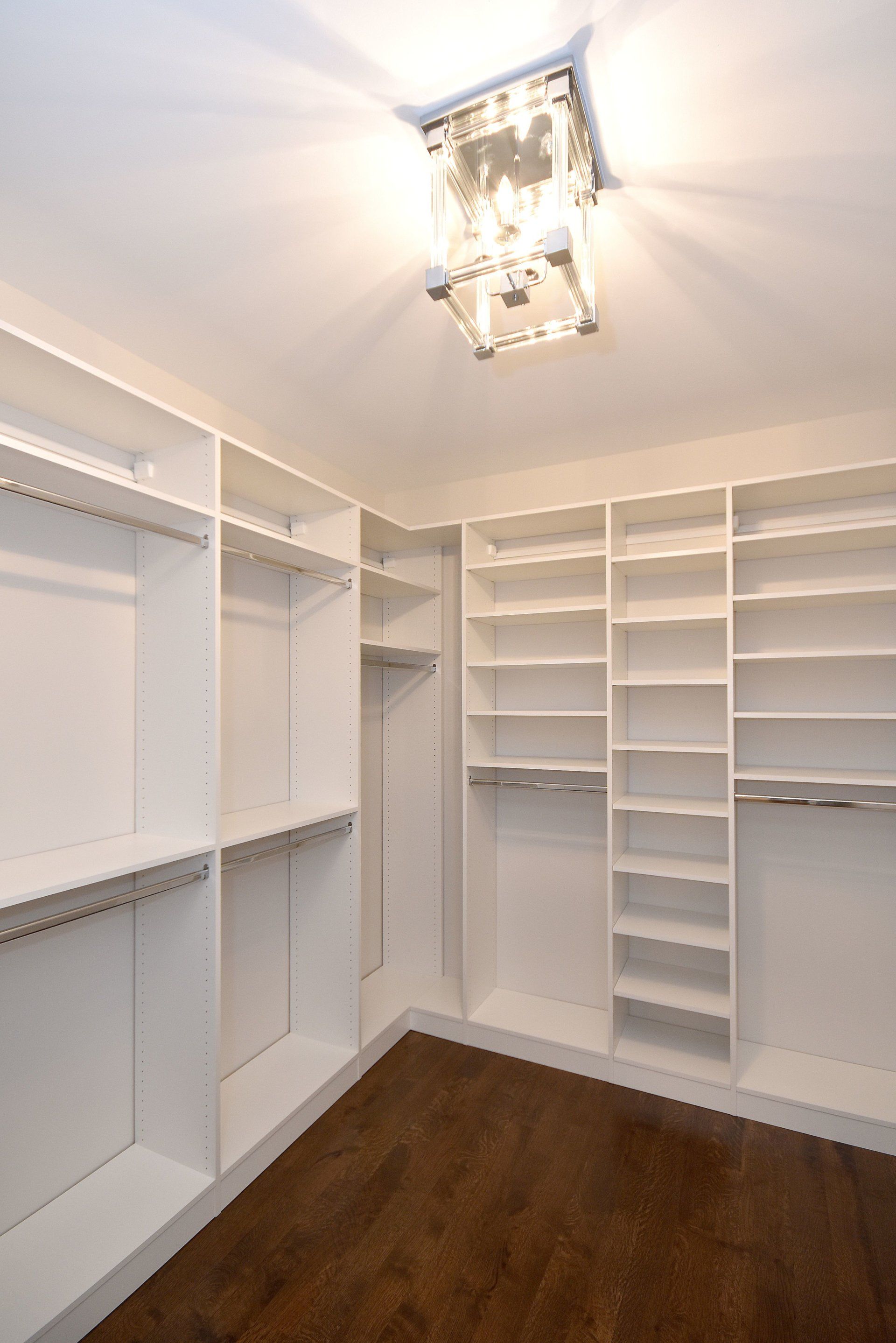A walk in closet with lots of shelves and a chandelier