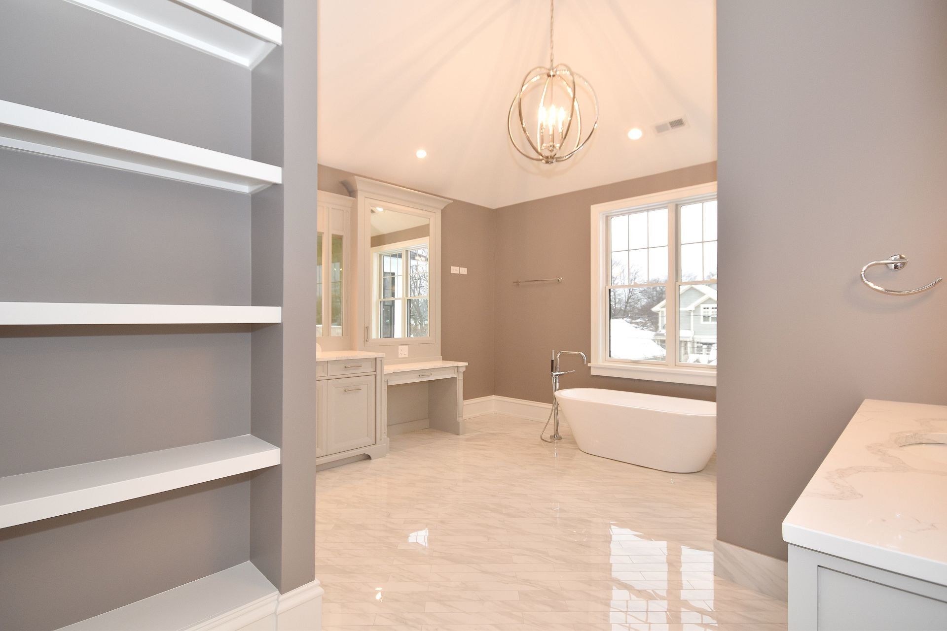 A bathroom with a tub , sink , mirror and shelves.
