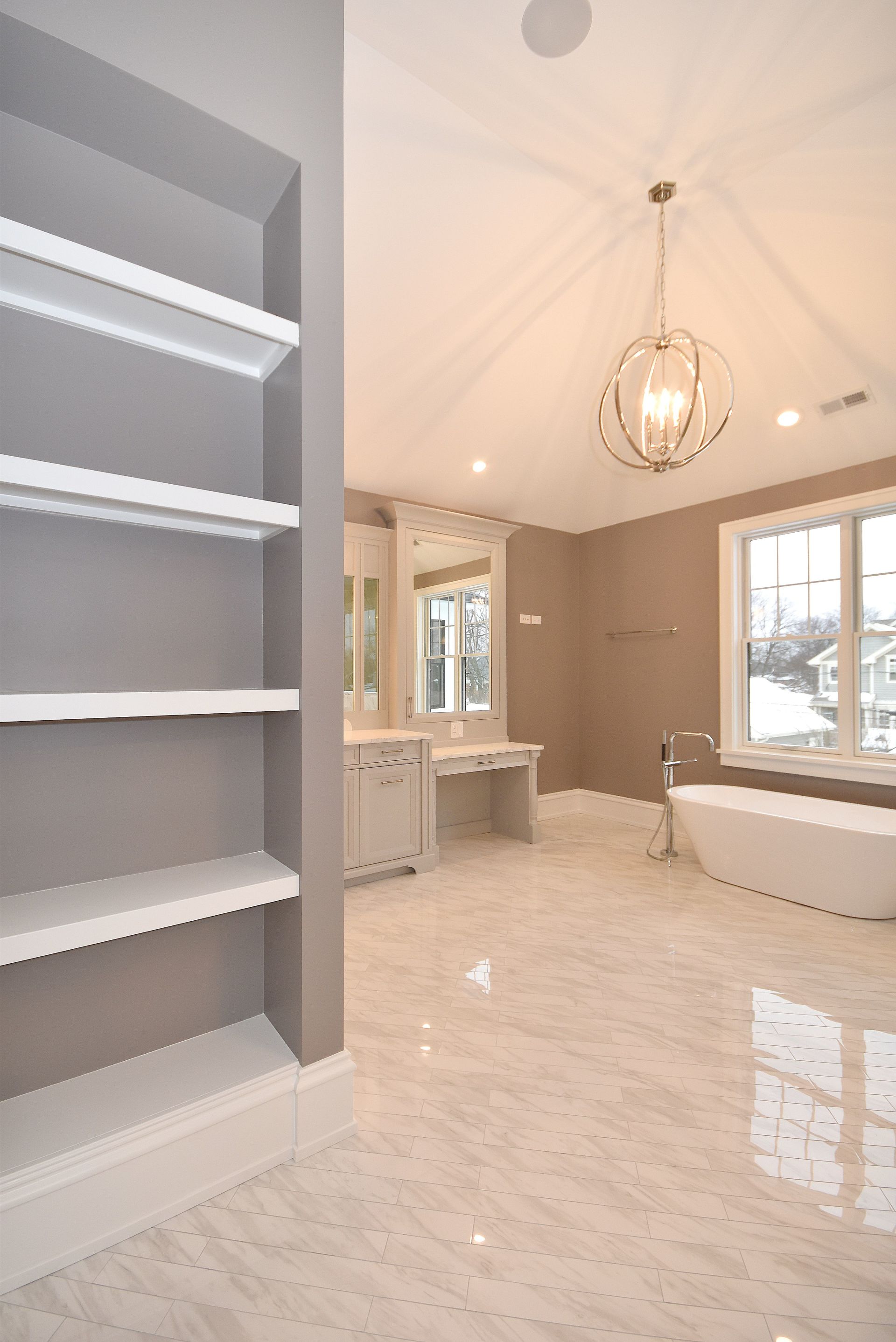 A bathroom with a tub , sinks , shelves and a chandelier.