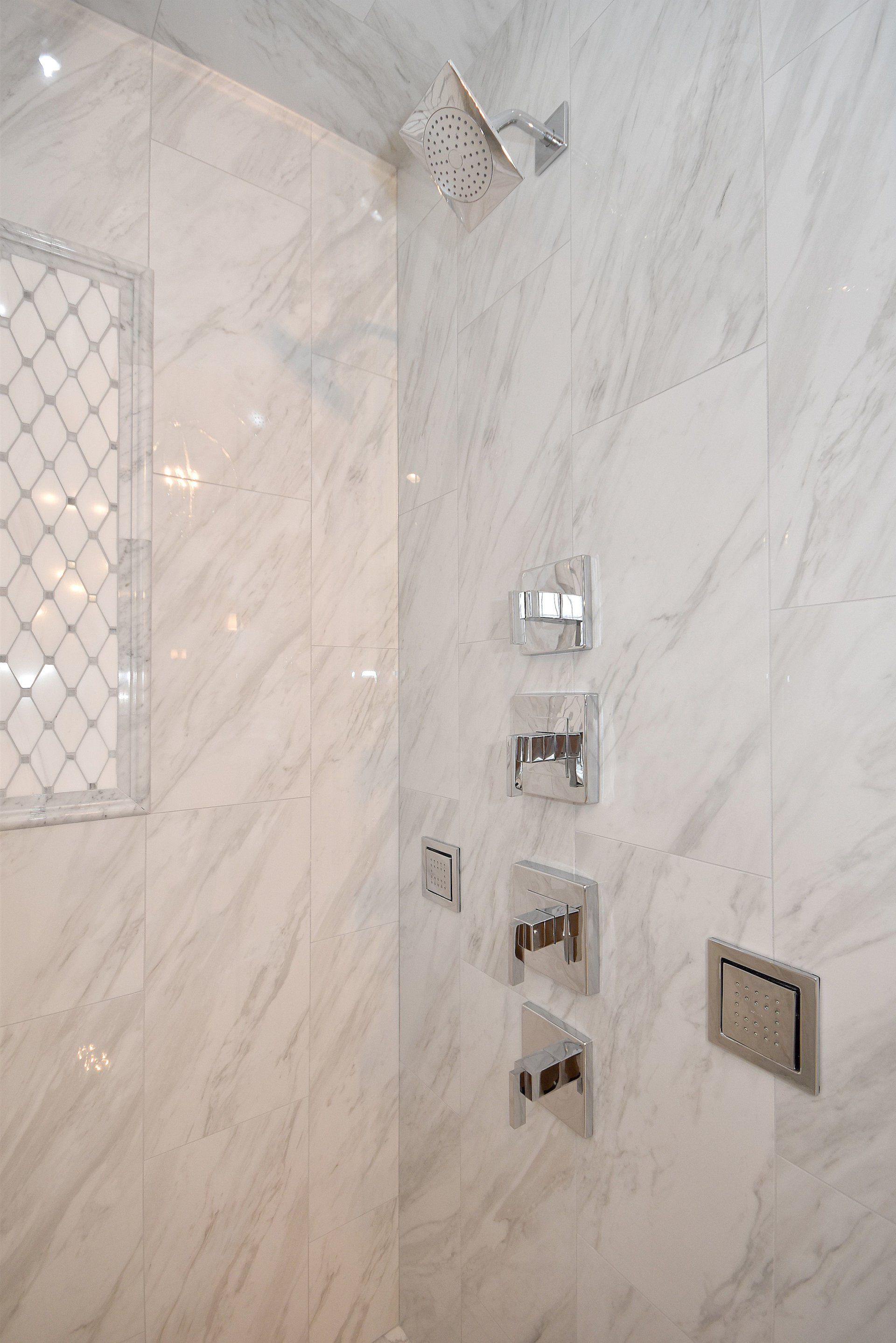 A bathroom with marble tiles and a shower head.