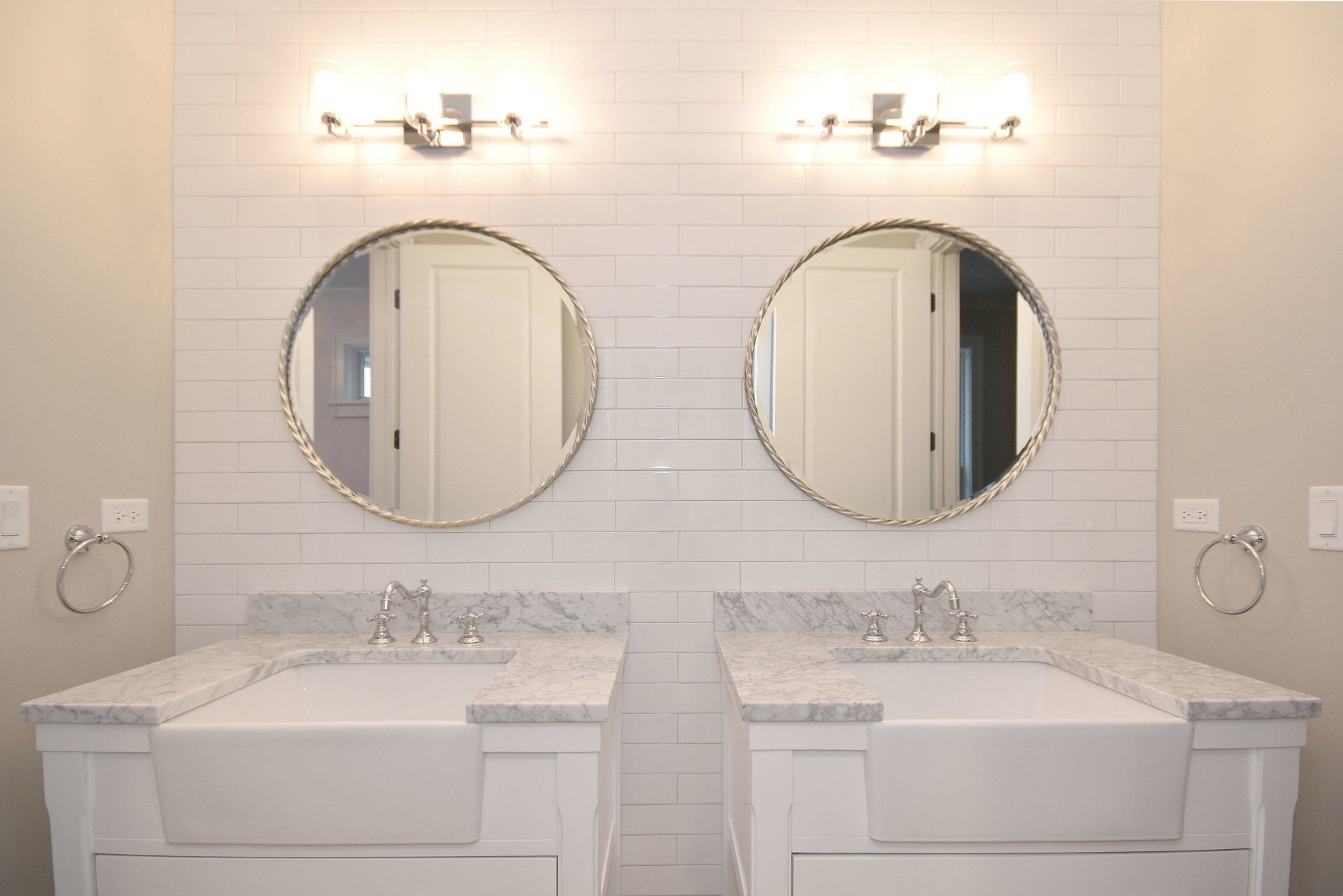 A bathroom with two sinks and two round mirrors.